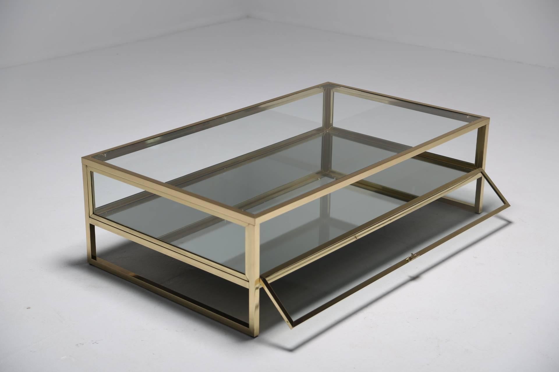 This French brass and glass curio display table really is the chicest way to display your beautiful collectibles. In immaculate condition, this stunning rectangular coffee table, dating back to the 1970s, has an elegant brass frame surrounded by