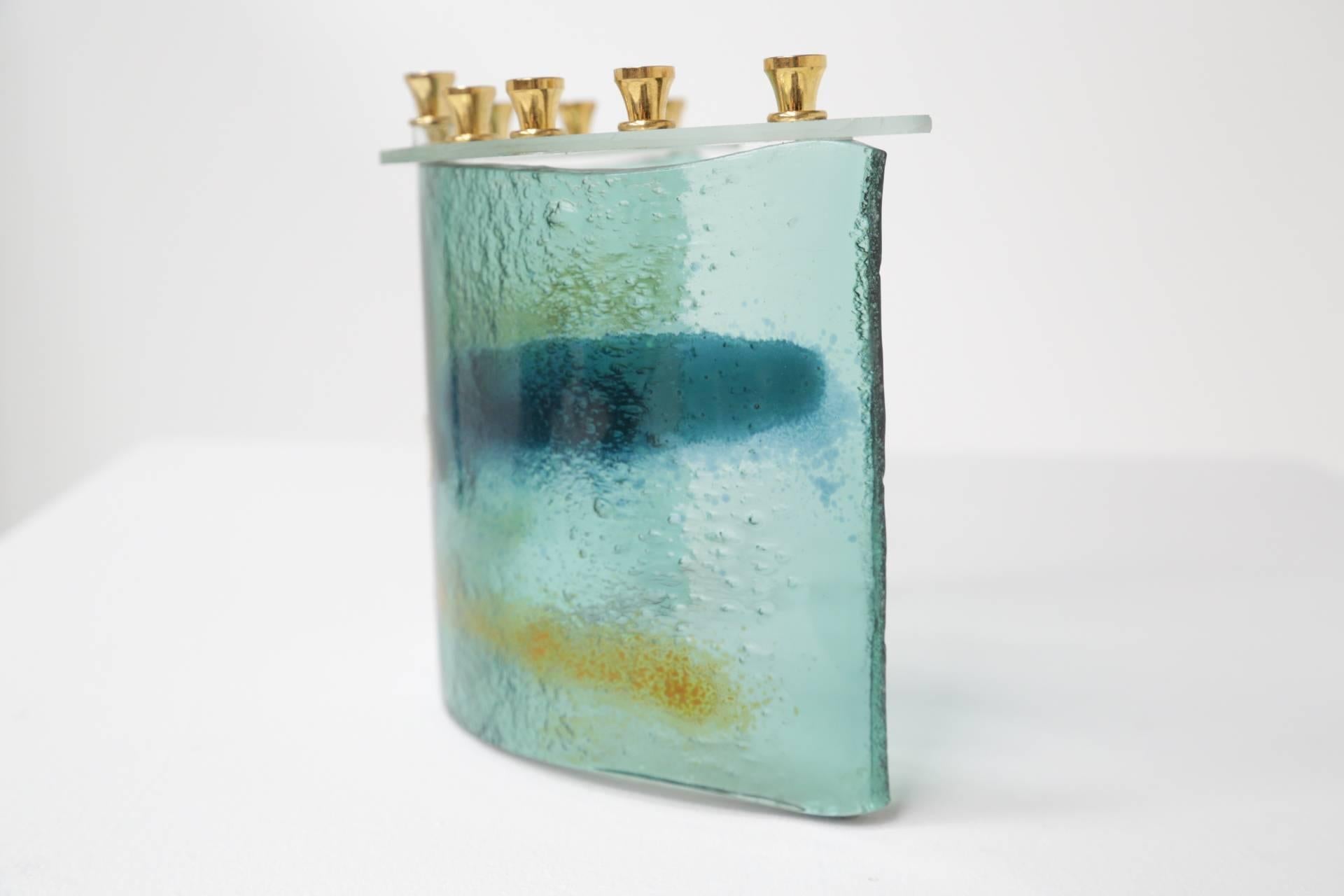 This is an absolutely sublime fused art glass Hanukkah menorah or hanukiah. Israeli Artist, Hanna Bahral, made this beautiful curved piece. She trained and honed her craft in the US before opening her shop in Jerusalem in 1956. Producing a large