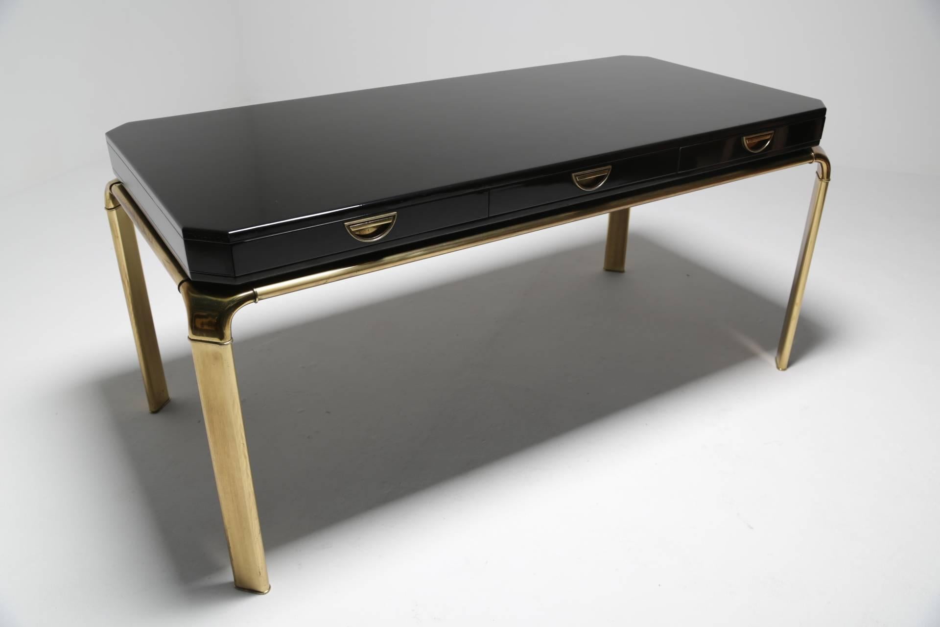 This is a luxe three-drawer desk by John Widdicomb Furniture Company and was made circa 1980. It is very much in the style of Hollywood Regency. A beautifully crafted brass frame and legs securely hold the black lacquer desk top. There are three