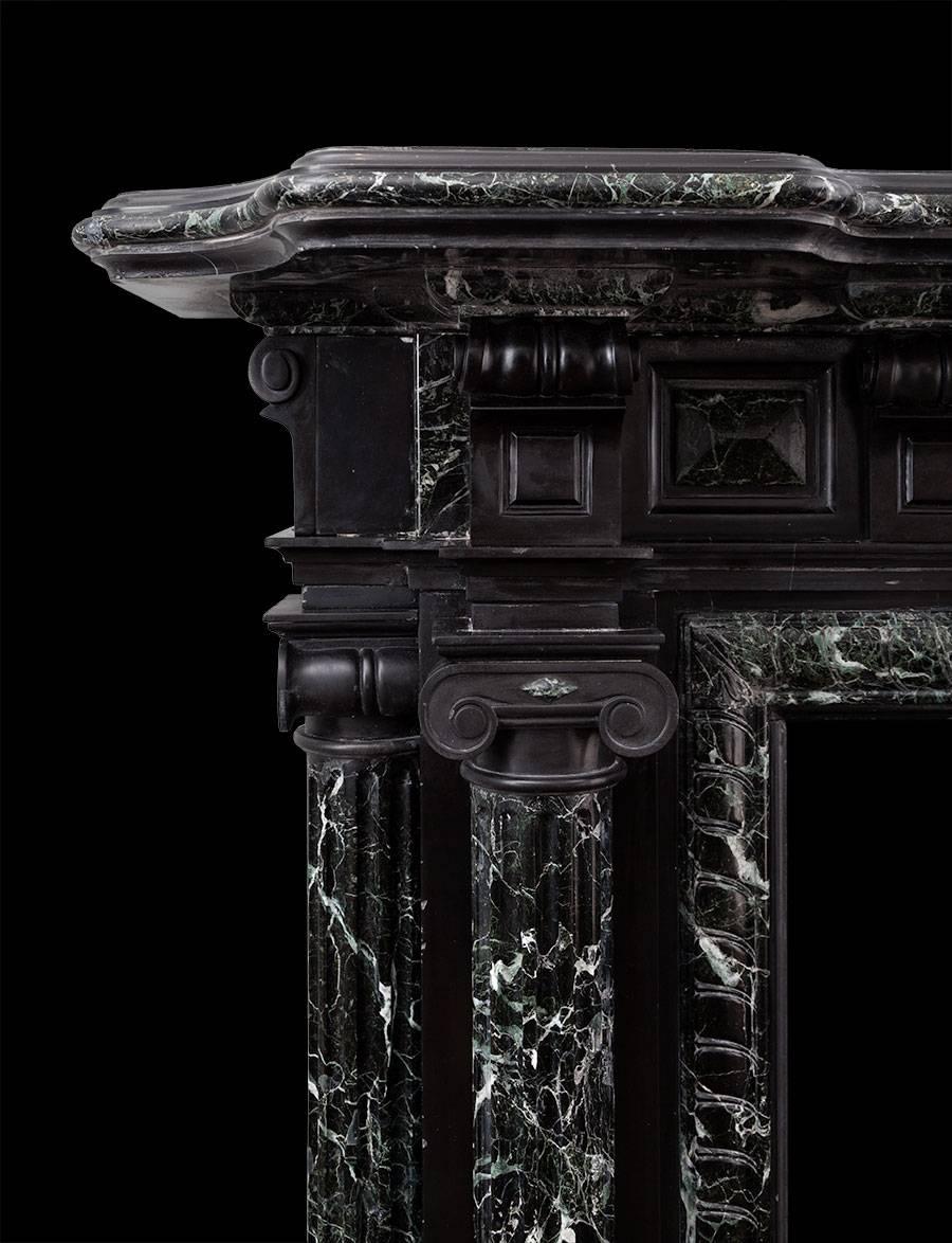 Antique English Victorian black and green marble mantelpiece. Dating from the 1860s, large in scale and made in the classical revival style. Each jamb as two fluted ionic columns, one on the front and the other on the side. The frieze consists of