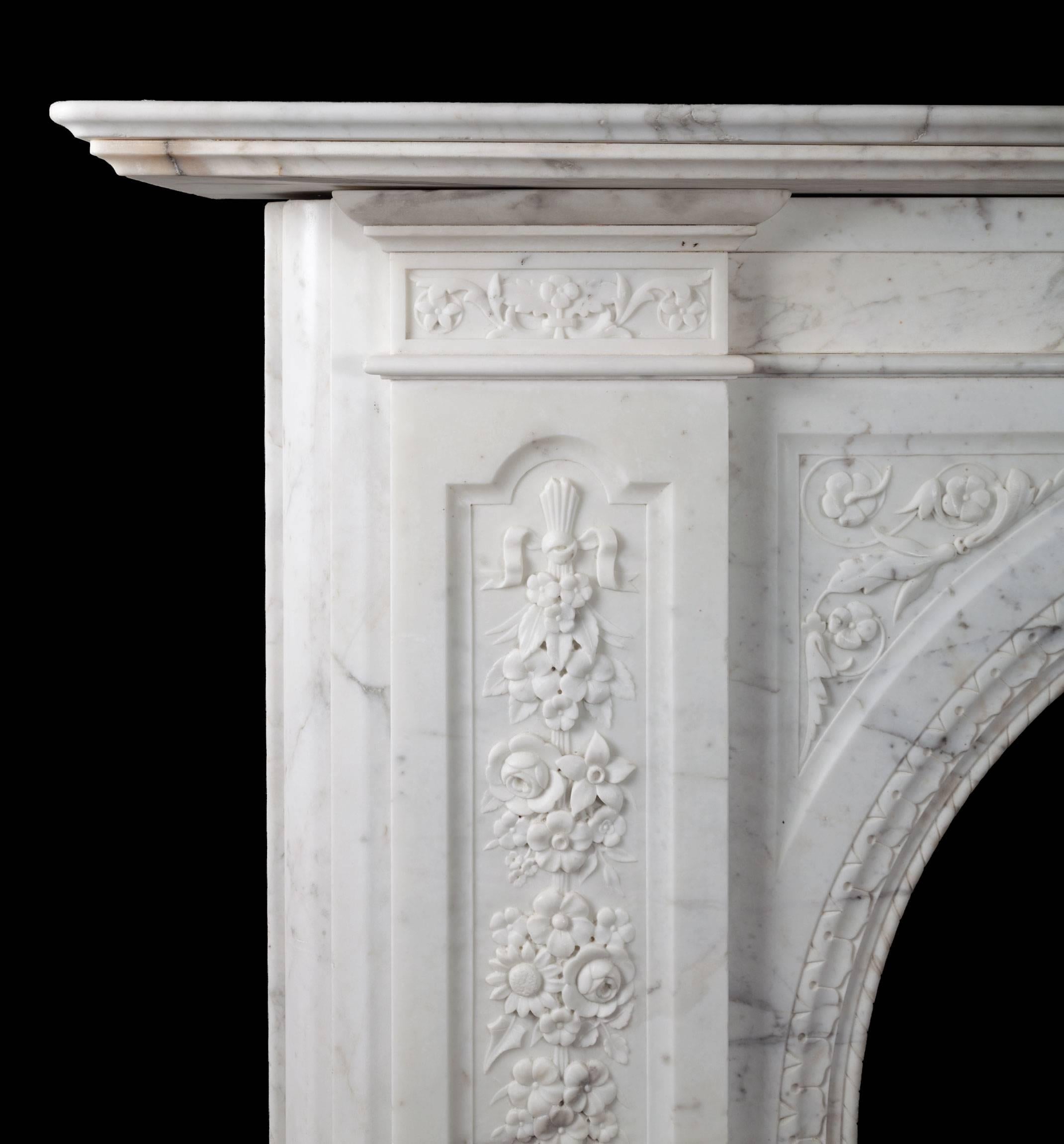 Large antique Victorian carved statuary Carrara marble fireplace. With profusely carved floral pilasters, arch spandrels and capitals. The arched fireplace opening edged with rope twist and leaf detail. The two arched panels centred with an acanthus