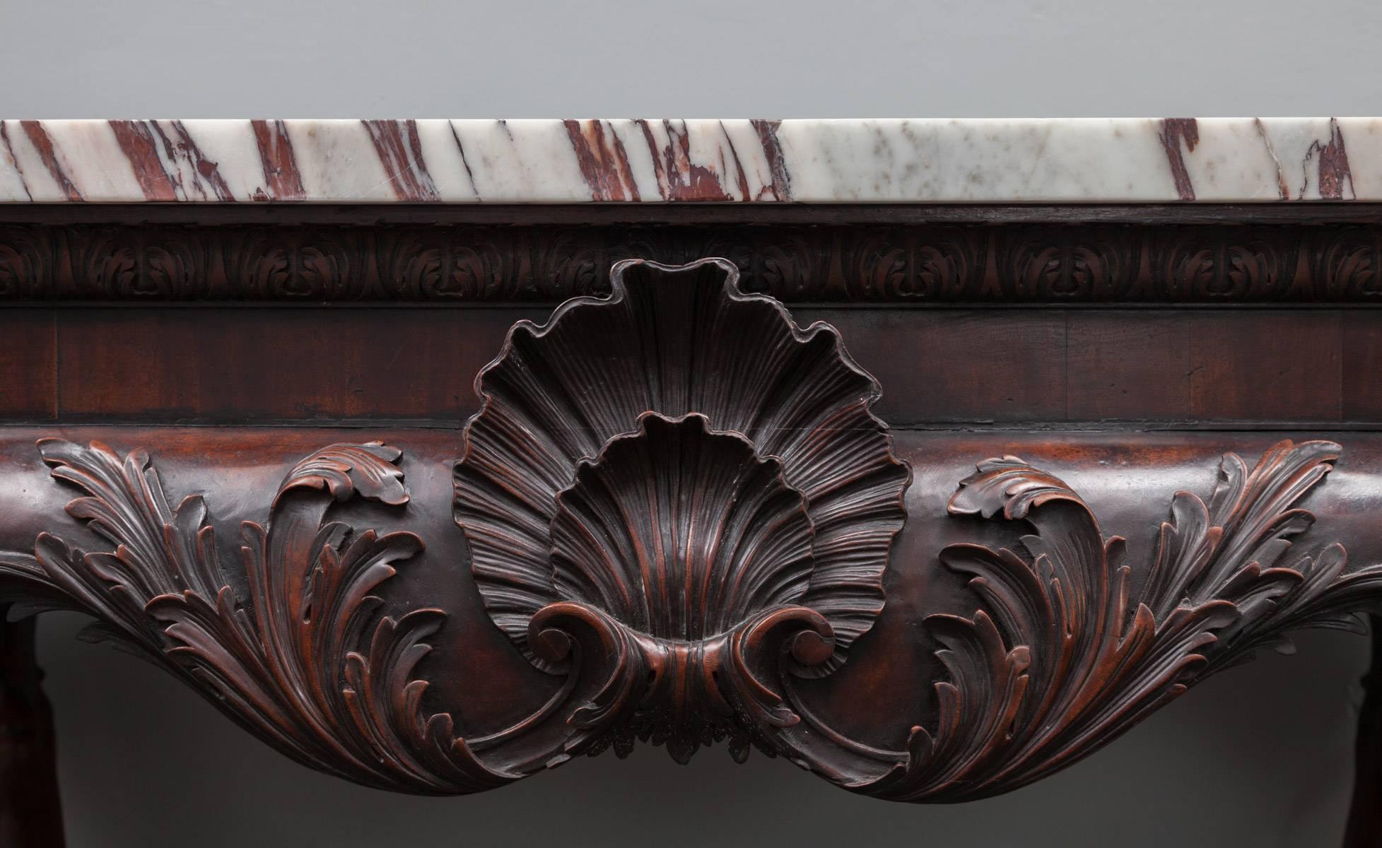 An outstanding 18th century mahogany side table with Breccia violetta marble top. The plain veneered frieze with acanthus moulded cornice supporting the solid Breccia violetta marble top. To the centre apron is a bold and beautifully carved double