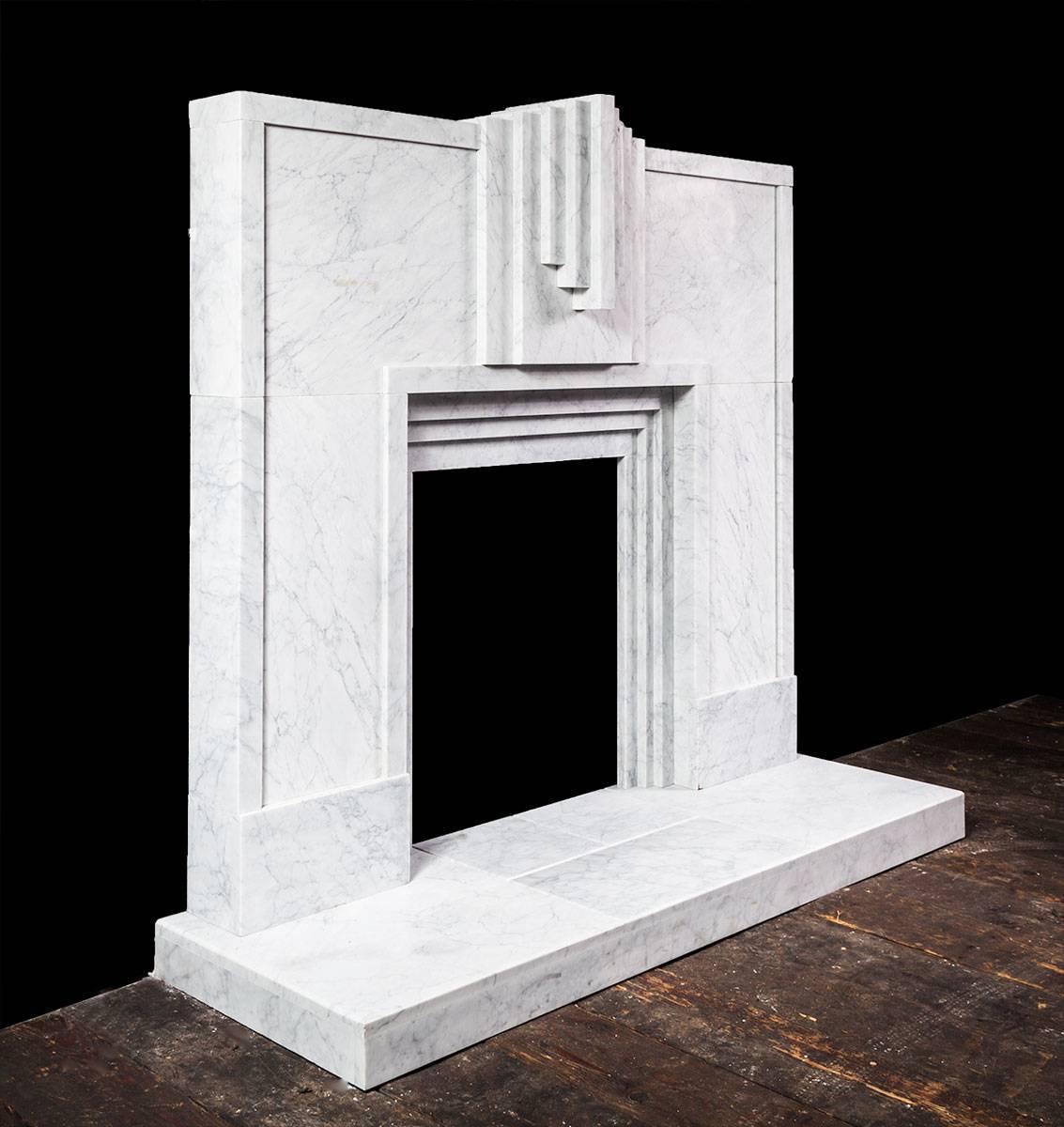 Der Kamin ist aus wunderschön geädertem italienischem Carrara-Marmor gefertigt und weist starke, klare und kühne geometrische Linien auf, die typisch für den Art-déco-Stil der 1920er Jahre sind.
   