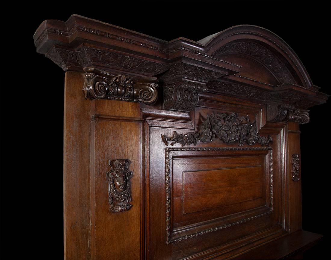 Antique Baroque style carved oak fireplace of large-scale.

The fireplace opening is framed with a wide moulding carved with egg and dart, above this is a mantelpiece. The overmantel section features a raised and fielded panel with a ribbon