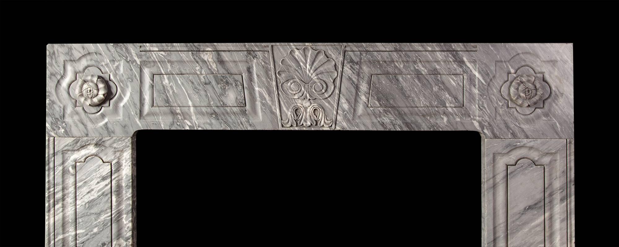 Carved from three pieces of Dove grey marble. The jambs and frieze having raised and fielded panels. The keystone carved with an oyster shell and the corners with stylized rosettes. This fireplace reflects the work of Irish stone cutter William