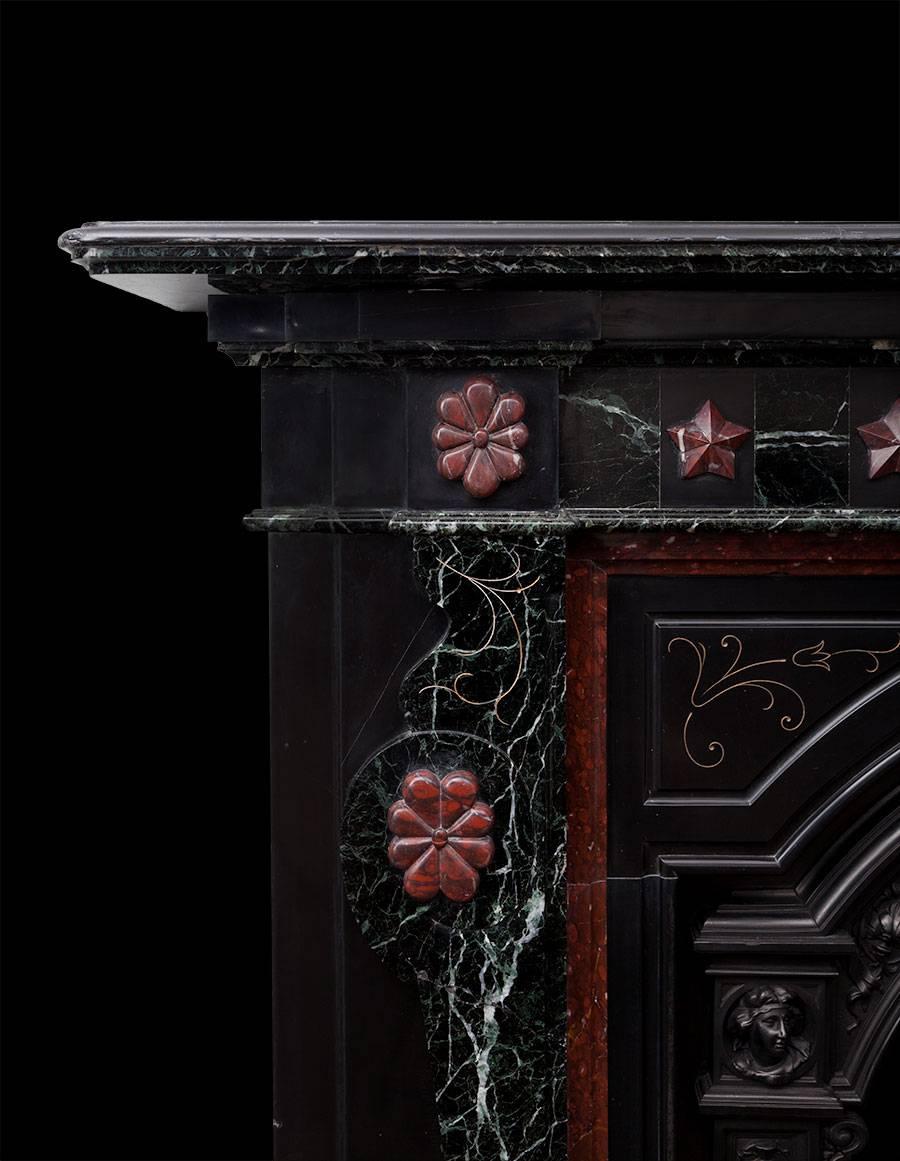 Made in London at the end of the 19th century, during the Aesthetic Movement. Three different types of European marble were sourced to produce this fireplace, Belgian Mazy Black, Greek Tinos Green and French Rouge Griotte. While several different