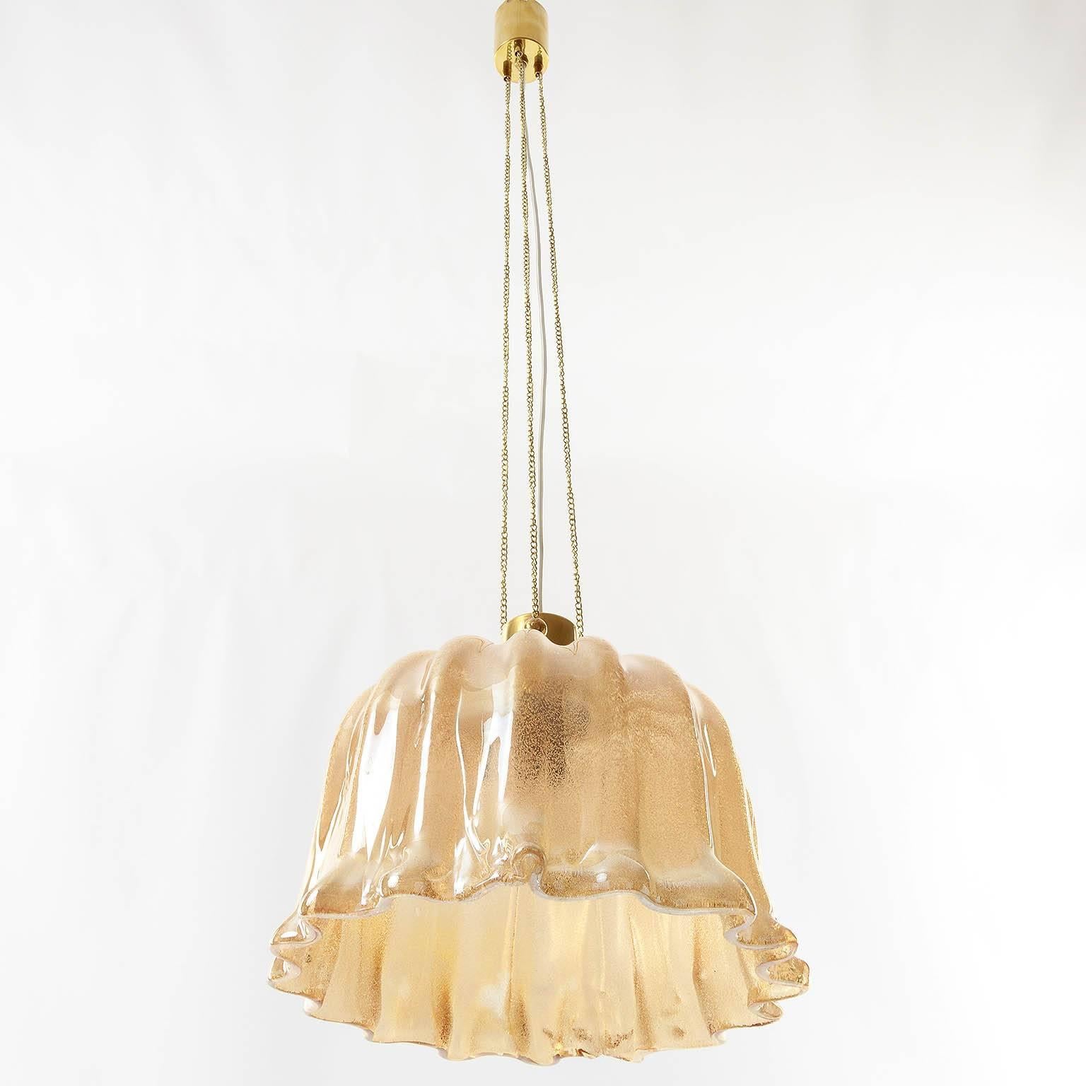 A beautiful Italian pendant light, chandelier attributed to Barovier e Toso, Italy, manufactuerd in Mid-Century (1960s - 1970s), ca. 1970. An amber tone Murano hand blown glass lamp shade hangs with chains ceiling cap. The brass parts are gilt.
The