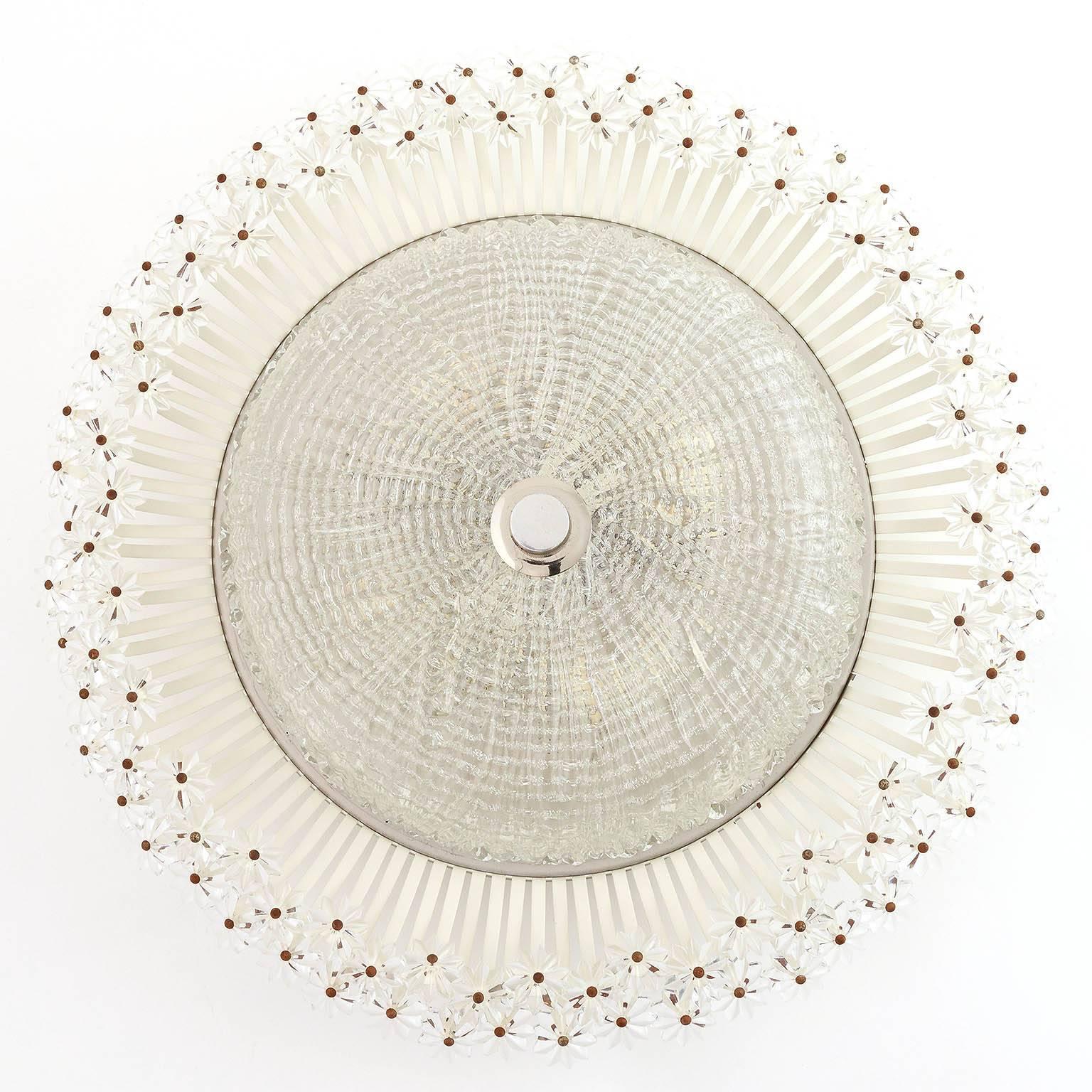 A rare and wonderful floral flush mount or wall lamp designed by Emil Stejnar and manufactured by Rupert Nikoll, Vienna, Austria, in Mid-Century, circa  1950. A textured glass is surrounded by hundreds of Lucite blossoms. 

There are several Emil