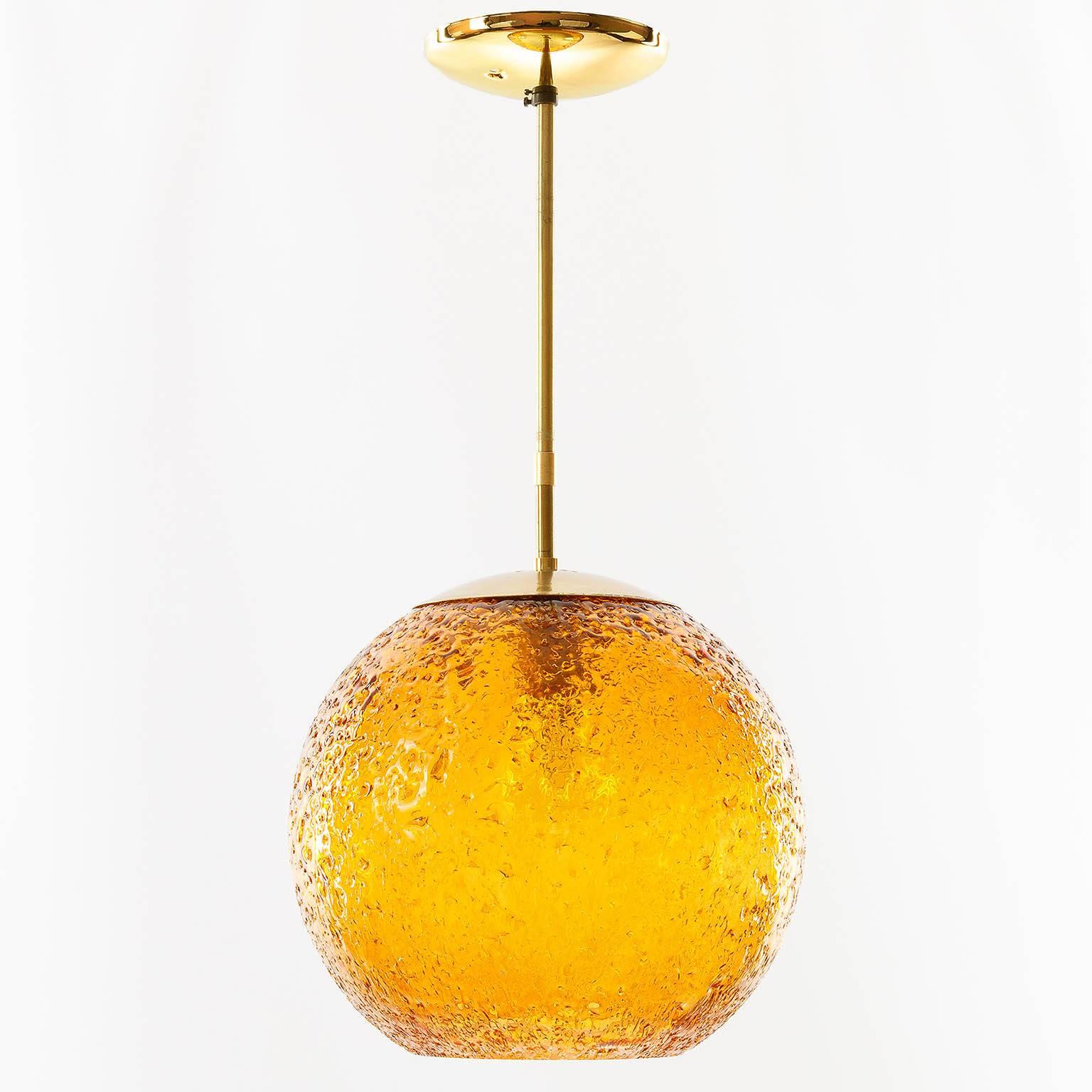 An amber tone (almost orange) glass globe pendant light with brass hardware. Produced in Germany in the 1970s. Very nice textured surface in a rich and warm color. One medium base bulb.
Current total drop: 20 inch.

Price reduced from $1200.