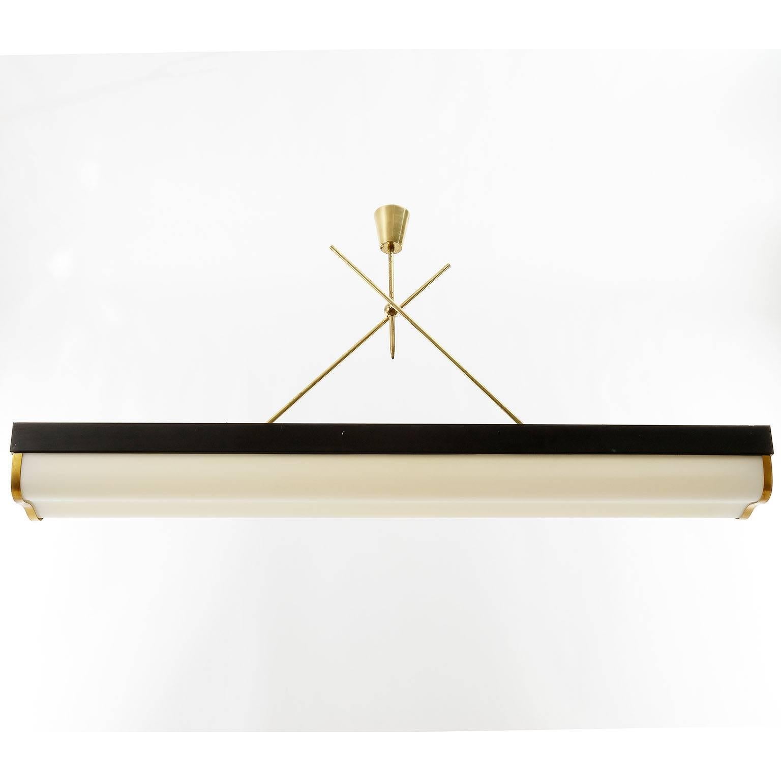 Impressive Italian light fixture by Stilnovo manufactured in the 1960s. A black lacquered and elongated metal frame holds two neon lamps which are covered by a curved lamp shade made of Lucite. The stem, canopy and details are made of brass with