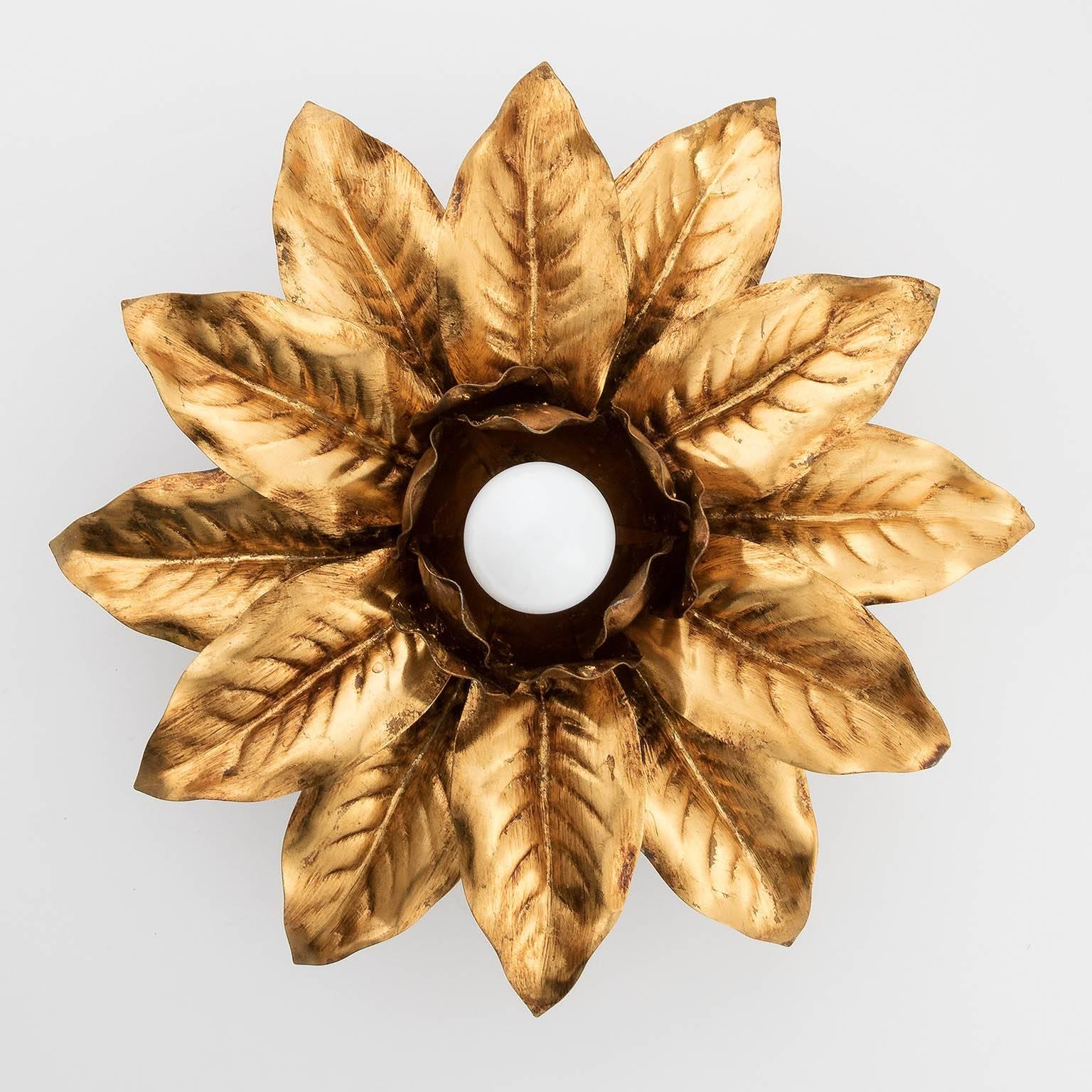 A pair of floral flush mount lights from Italy, manufactured in Midcentury. They are made of antique gilt or bronzed metal. A medium Edison base bulb is like a bud in the middle of centered arranged leaves.