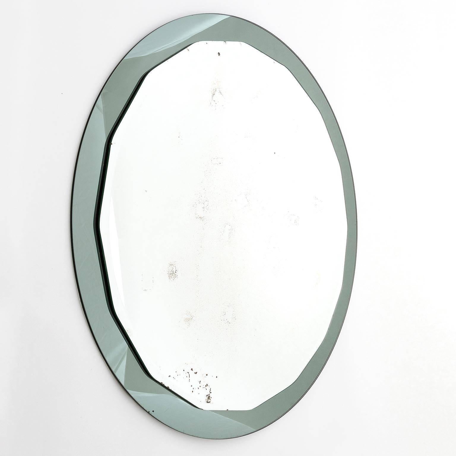 An Italian wall mirror manufactured in Mid-Century in 1960s. It is made of a round, scalloped faceted mirror with a smoked grey mirror backplate glass. Vintage condition with noticeable wear and stains on the surface.