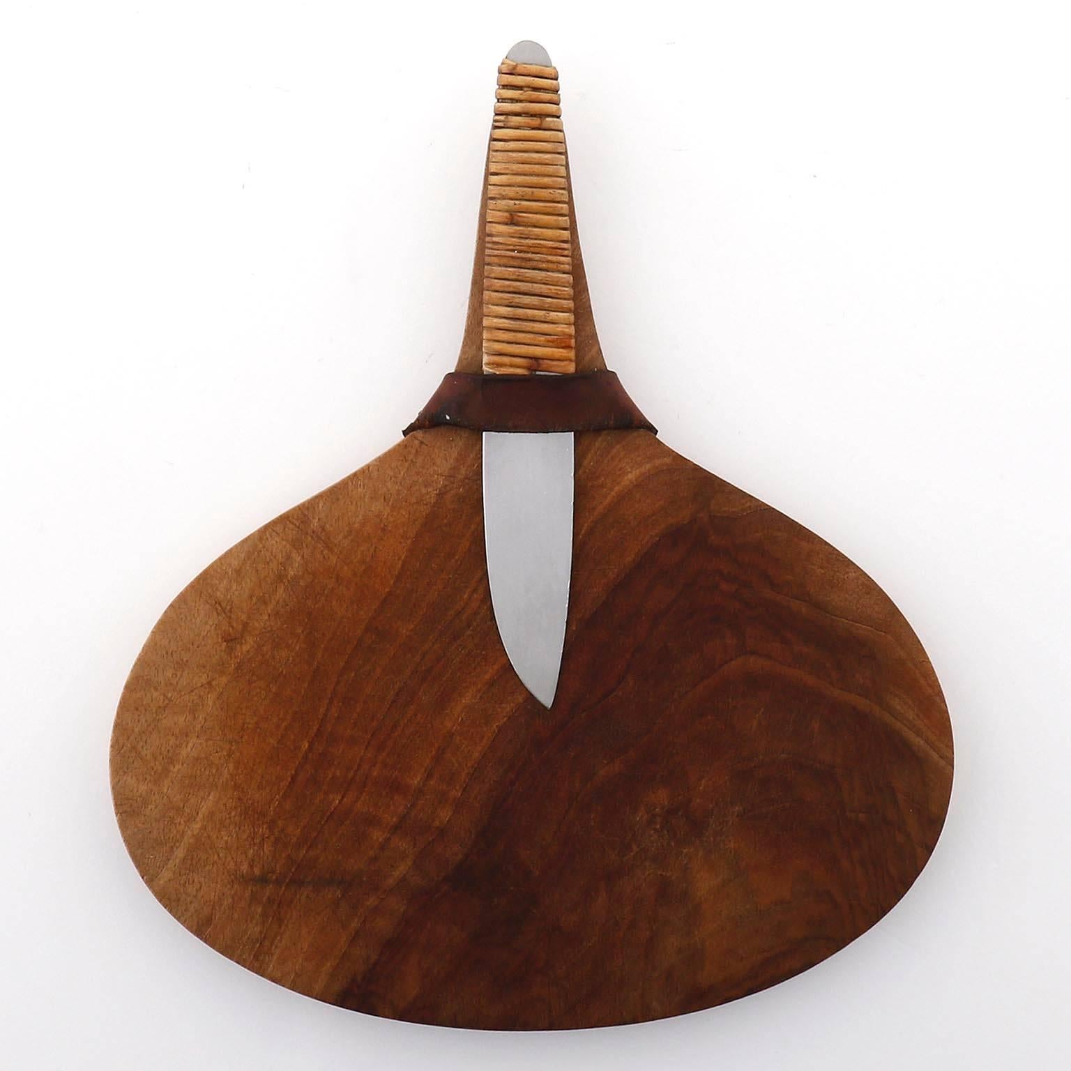 A cutting board by Carl Auboeck / Aubock, Vienna, manufactured in Mid-Century in circa 1950.
A wooden board with a leather strap to hold a knife made of a wicker grip and stainless steel.
