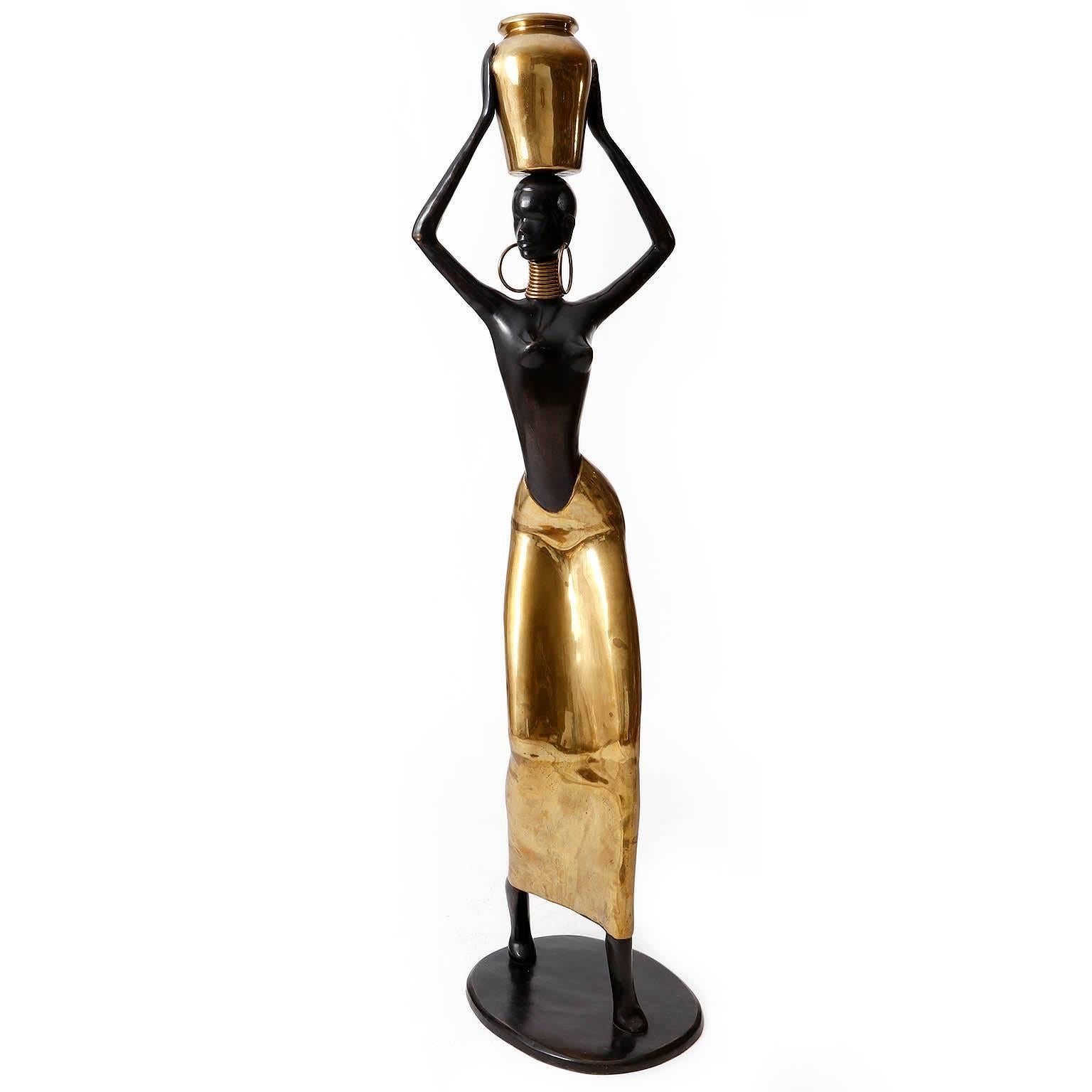 A large and beautiful African woman figurine made of polished and blackened brass manufactured in Mid-Century in the 1950s.
Little and lovely patina on brass. A gorgeous and eye-catching piece.