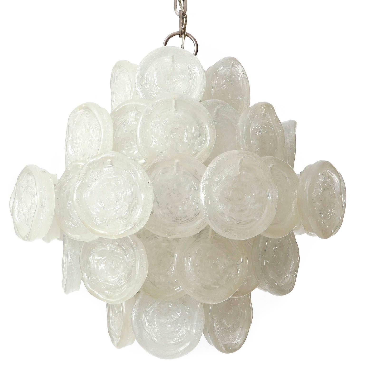 A large and wonderful multi-tiered chandelier in the style of Kalmar, Austria, manufactured in Mid-Century, circa 1970. 
Round discs made of Lucite hanging on a white lacquered metal frame. The layered Lucite elements create a wonderful light. Chain