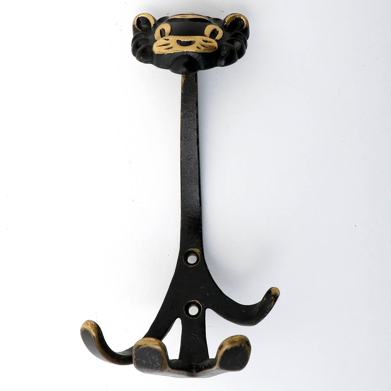A coat wall hook in the form of a lion by Walter Bosse, Austria, manufactured in Mid-Century, circa 1950.
It is made of blackened and partly polished brass. Wear of use, lovely patina.

There are also other animal hooks in the form of a monkey, a