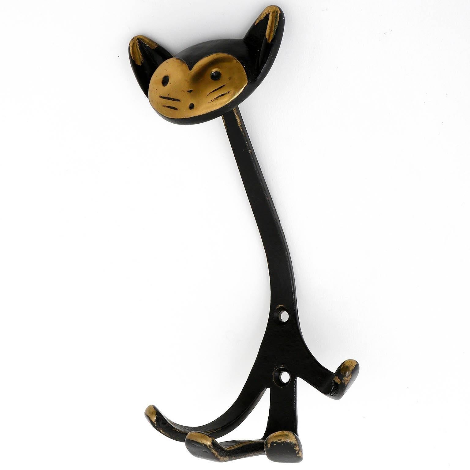 A coat wall hook in the form of a cat by Walter Bosse, Austria, manufactured in Mid-Century, circa 1950.
It is made of blackened and partly polished brass. Wear of use, lovely patina.

There are also other animal hooks in the form of a monkey, a