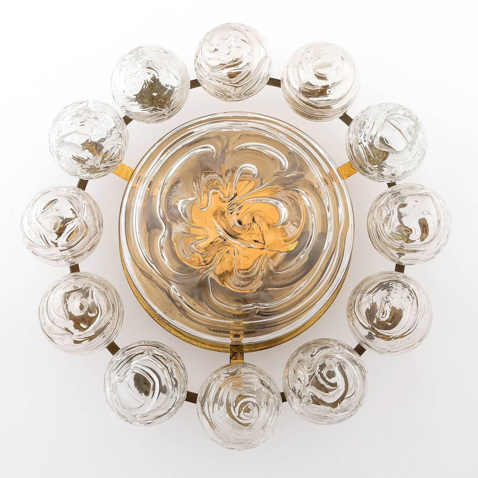 A flush mount light fixture by Doria Leuchten, Germany, manufactured in Mid-Century, circa 1960.
The lamp is made of a brass frame which holds 12 handblown glass balls and one glass disc in the centre. Each glass ball has a diameter of 3.2