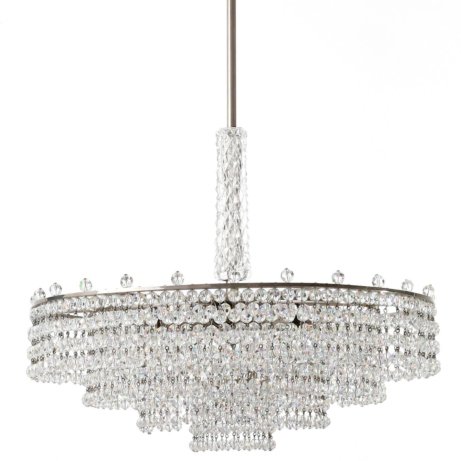 A beautiful chandelier by Palwa (Palme & Walter), Germany, manufactured in midcentury, circa 1960.
It is made of a nickel-plated brass frame decorated with chains of cut crystal glass beads. A part of the rod is covered with a textured glass tube.