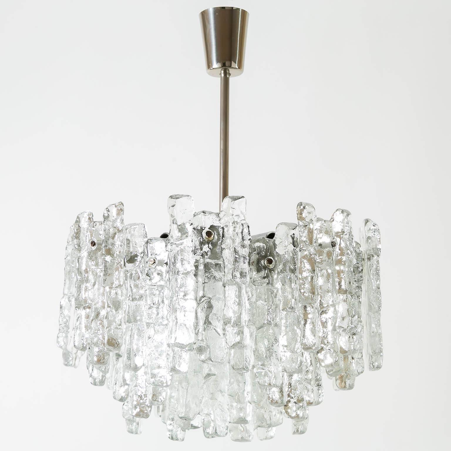 Two beautiful ice glass light fixtures by Kalmar, Austria, manufactured in Mid-Century, circa 1970 (1960s-1970s). Each chandelier is made of 28 massive ice blocks which are mounted on a silver painted metal frame. The stem and canopy are made of