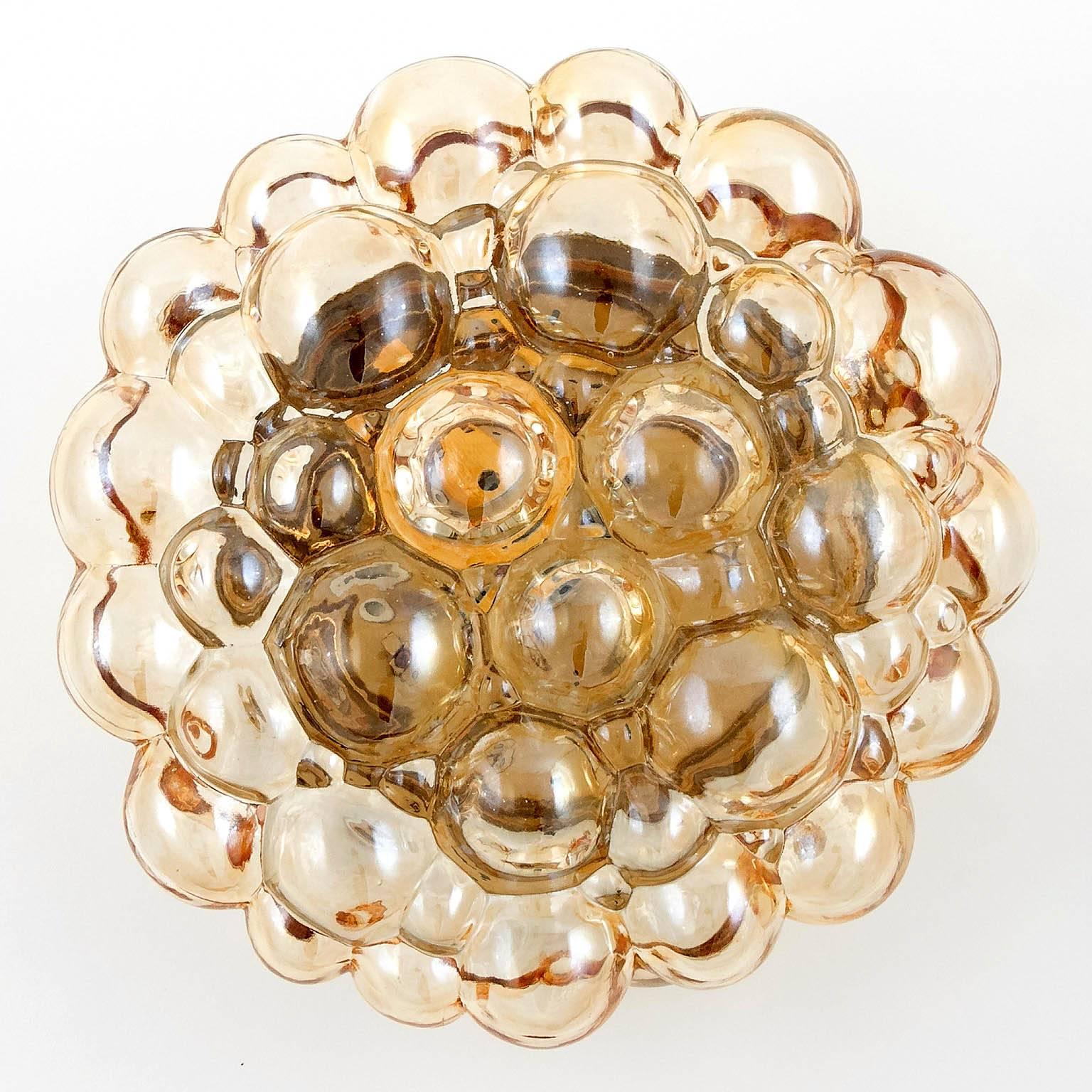 A pair of round vintage amber bubble glass lights, manufactured in Mid-Century.
They can be used as wall sconces or flush mount lamps. 
The lights were designed in the 1960s by Helena Tynell & Heinrich Gatenbrink for Glashütte Limburg, Germany.