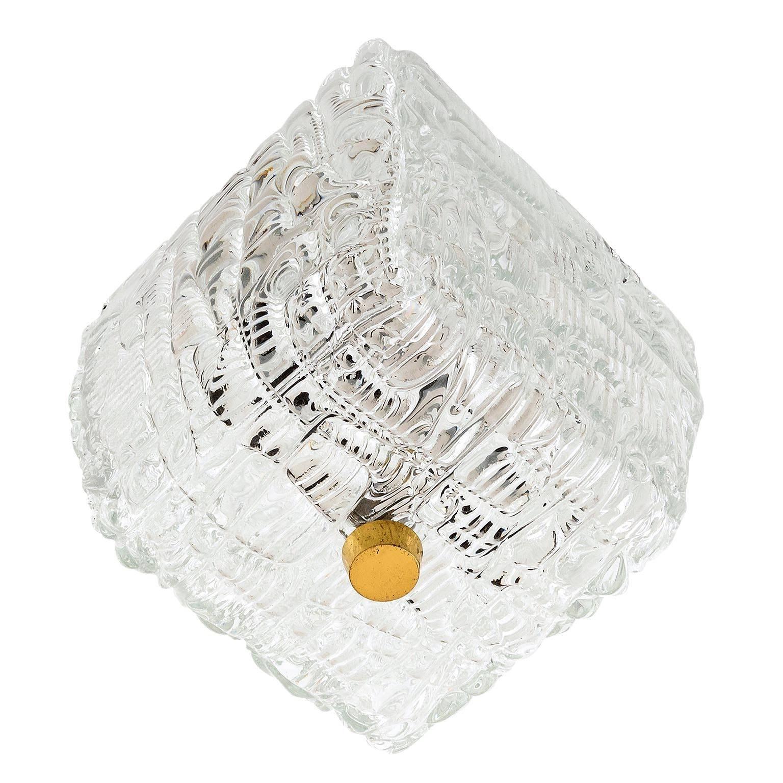 One of two flush mount light fixtures by Kalmar, Austria, manufactured in Mid-Century, circa 1960 (late 1950s or early 1960s). 
A textured clear glass is mounted with a brass knob to a backplate. 
The lamp has two sockets for small screw base LEDs