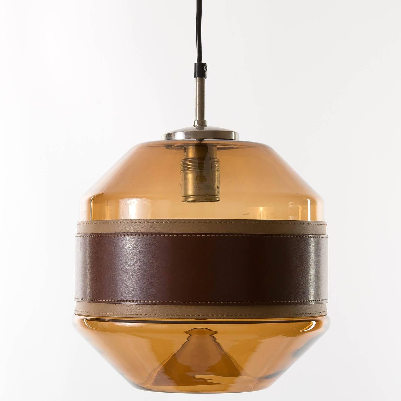 Beautiful and very rare glass pendant light or chandelier by Kalmar, manufactured in Mid-Century circa 1970 (at the end of 1960s and beginning of 1970s). It is made of a chromed hardware and an amber toned glass body with a belt made of two layers