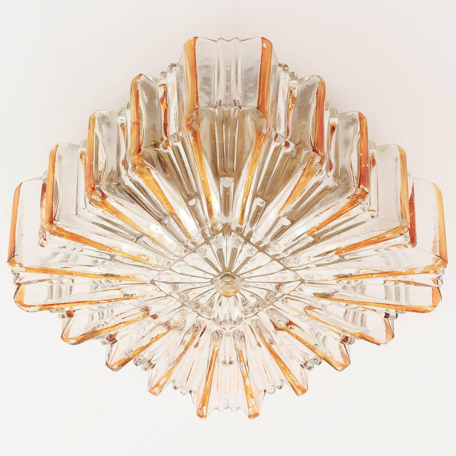 A vintage pair of glass flush mount sunburst sconces, manufactured Midcentury. Glass shades with amber tone rays and a gold toned circular backplate. Some wear, patina on backplate, can be repainted for free if required. Some flaking to the colored