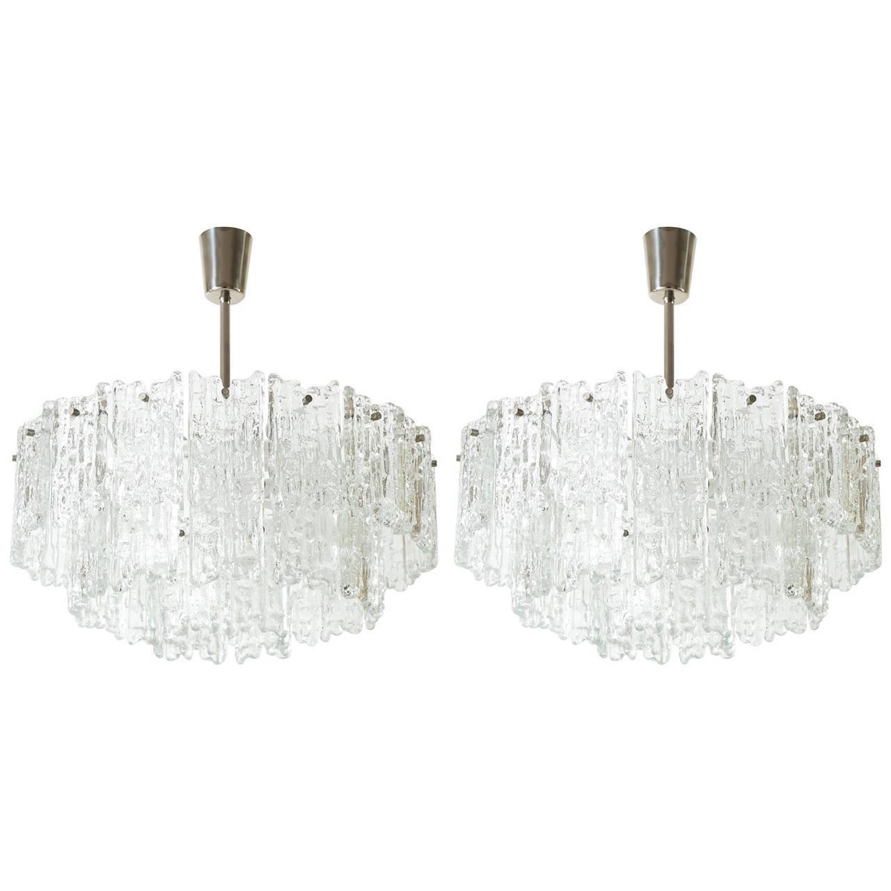 A set of two beautiful icicle glass chandeliers with a 'Finger' pattern by J.T. Kalmar, Austria, manufactured circa 1960. Each light fixture is made of frosted glass blocks which are hanging on a white lacquered hardware. Each chandelier has nine