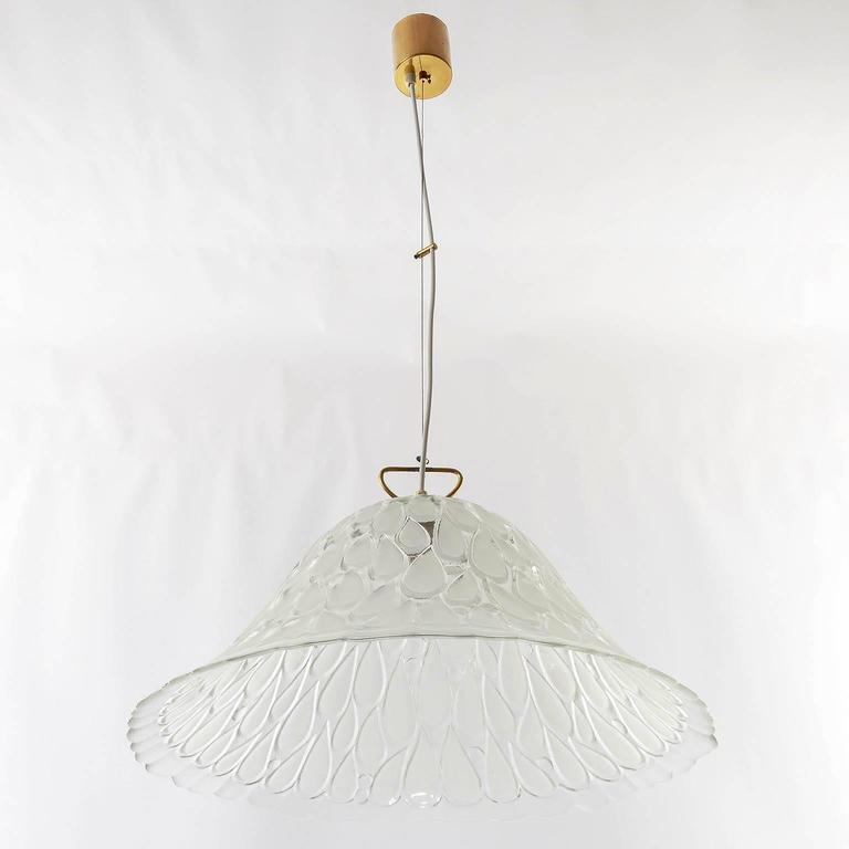 Rare and exceptional pendant light fixture by Kalmar, Austria, manufactured in the 1960s-1970s. A large textured glass shade with drop shaped engravings is hanging on a brass mounting. The height can easily be adjusted to any size.
Labeled with