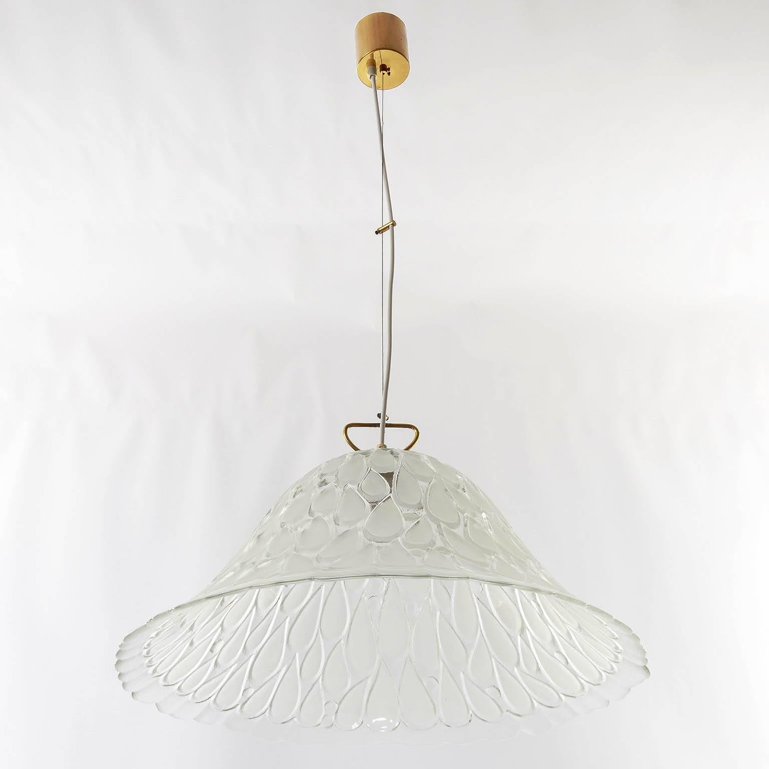 A rare and exceptional pendant light fixture by Kalmar, Austria, manufactured in the 1960s-1970s. A large textured glass shade with drop shaped engravings is hanging on a brass mounting. The height can easily be adjusted to any size.
Labeled with