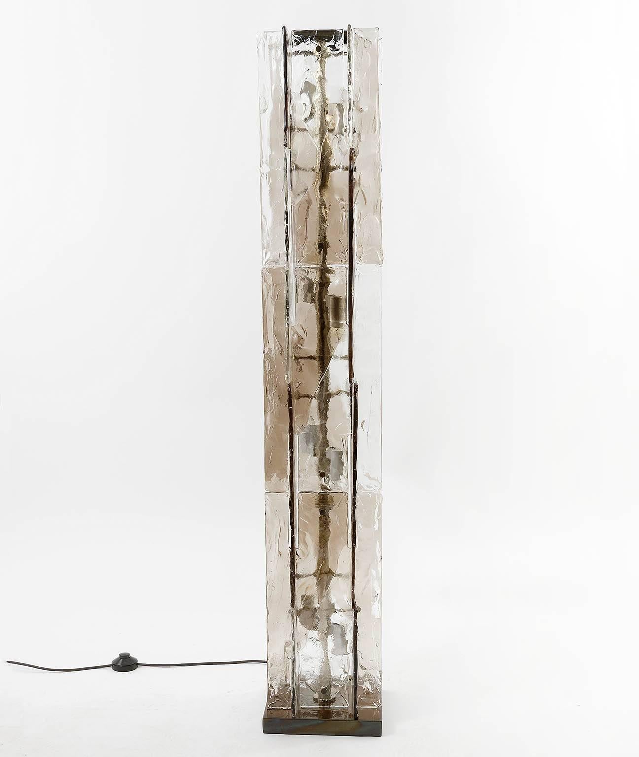 A beautiful Italian modernist floor lamp by Carlo Nason for Mazzega, manufactured in Mid-Century, circa 1970 (late 1960s or early 1970s). 
A metal frame holds several interlocking smoke and clear Murano glasses. It takes eight small screw base E14