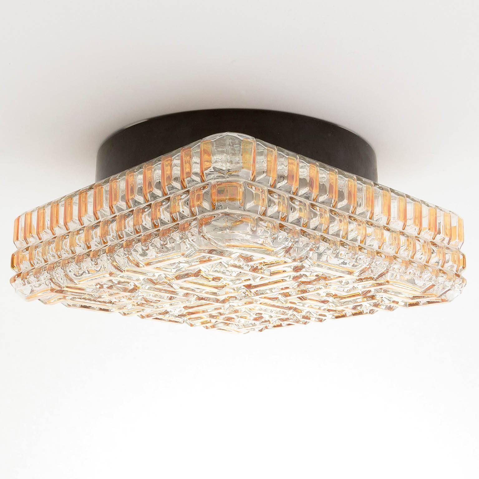 A square and unusual light fixture in the style of Glashütte Limburg, manufactured in Germany in Mid-Century, ca. 1970. A clear textured glass with geometrical patterns with orange or amber tone painting. An original vintage piece in excellent