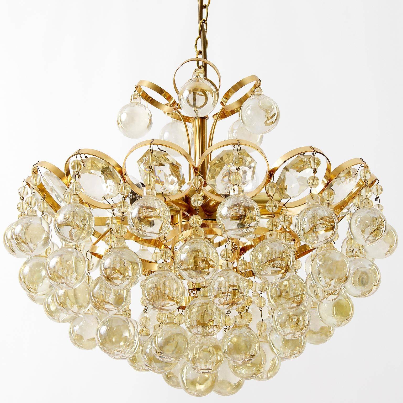 A wonderful and rare version of a gold-plated brass chandelier with amber tone crystal glass pieces by Palwa, Germany, manufactured in Mid-Century, circa 1970 (1960s-1970s). It has six sockets for small Edison screw base bulbs type E14 (max. 40W per