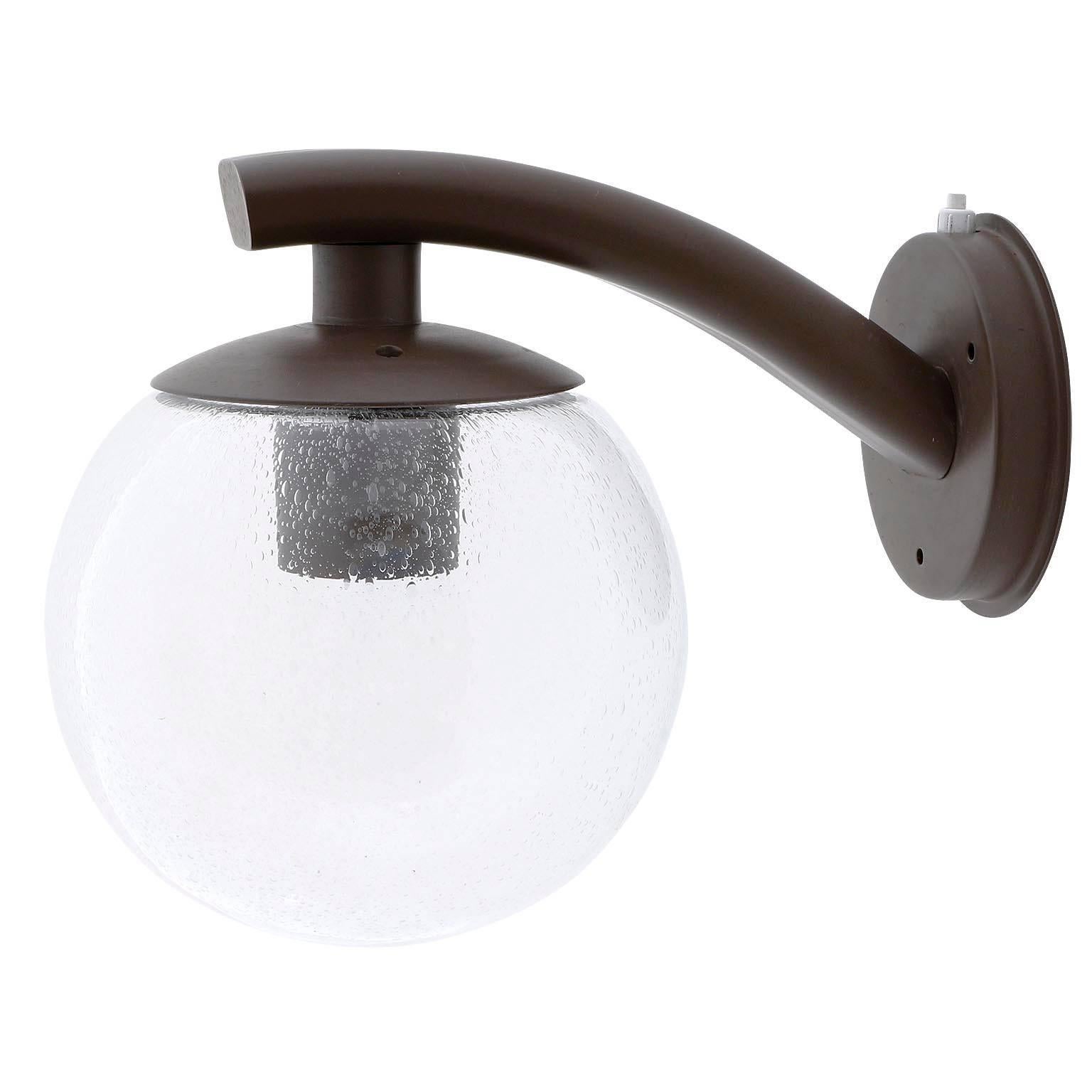 One of eight wall lamps model C-1612 by RAAK Amsterdam, Netherlands, manufactured in Mid-Century, circa 1970. A lamp as an outstreched hand. A dark brown powder-coated metal arm holds a clear bubble glass globe. An integrated switch can also be