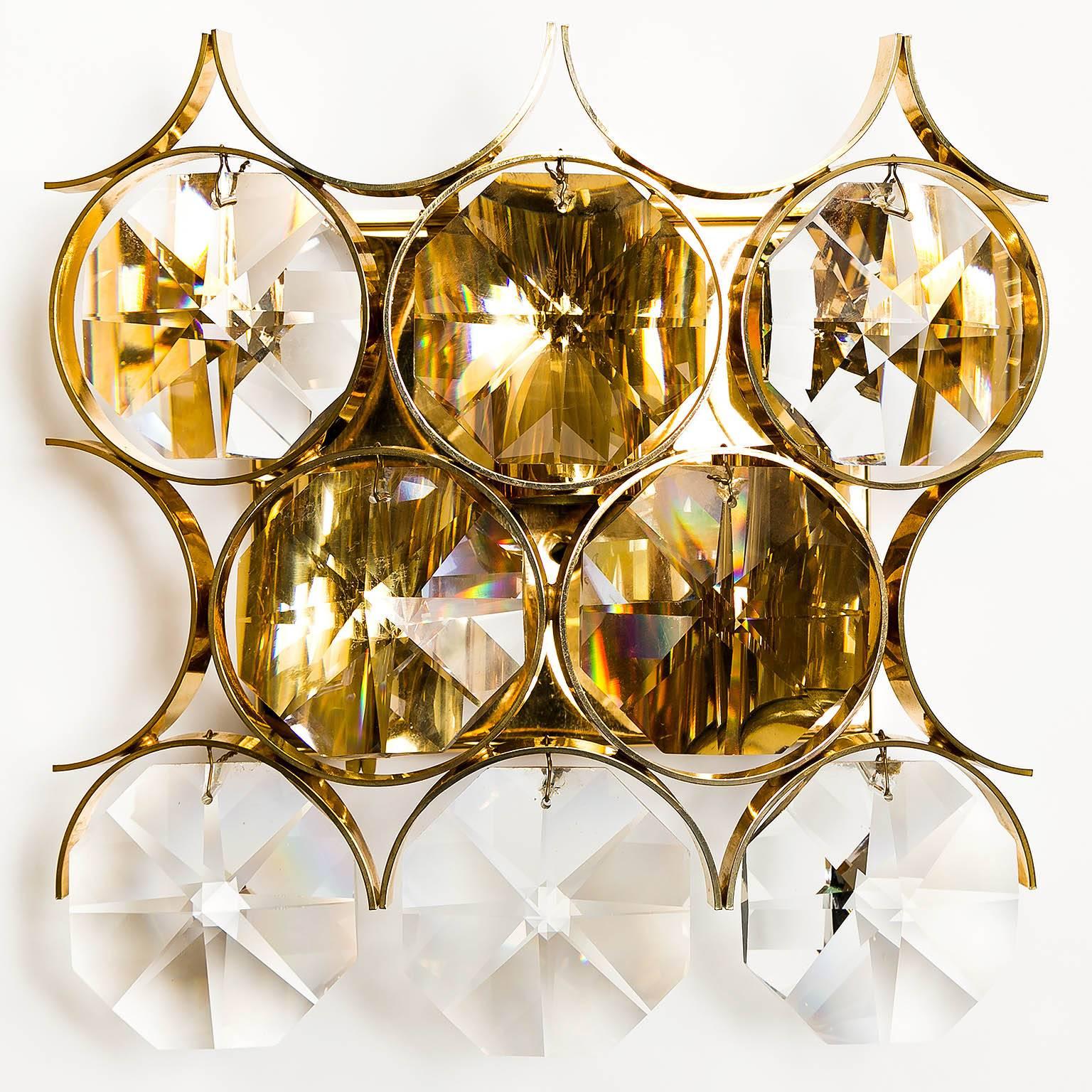 A pair of beautiful wall lights by Palwa (Palme and Walter), Germany, manufactured in midcentury, circa 1970 (1960s-1970s).
The lamp shades are made of gilded / gilt / gold-plated brass rings and large crystal glasses. 
The backplates are made of