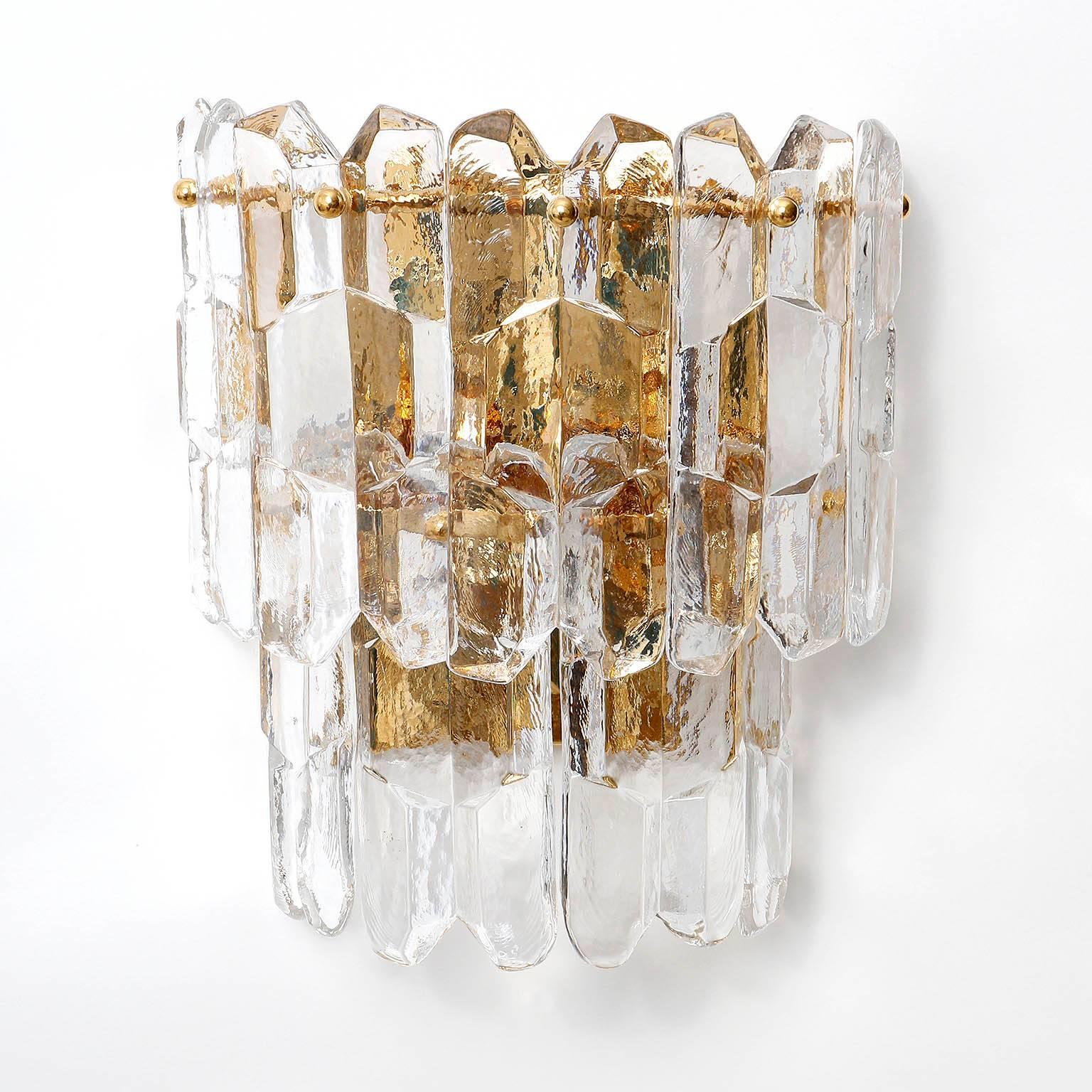 A pair of very exquisit 24-carat gold-plated brass and clear brillant glass 'Palazzo' wall lights by J.T. Kalmar, Vienna, Austria, manufactured in circa 1970 (late 1960s and early 1970s). 
These large hollywood regency lamps are handmade and high
