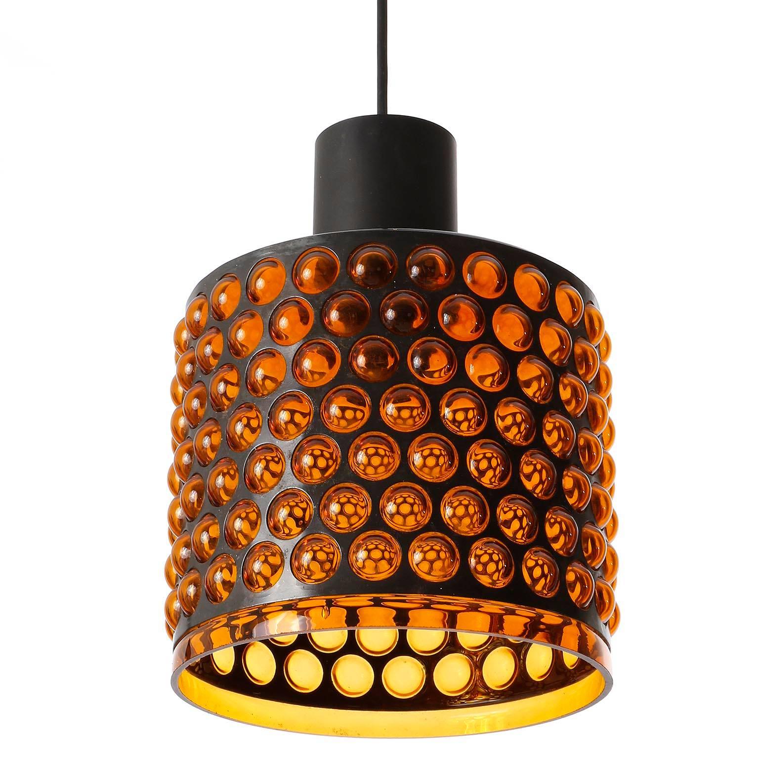 A pendant light made of a perforated metal belt and orange plexiglass, manufactured in Mid-Century, circa 1970 (late 1960s or early 1970s).
The acrylic glass has been blown through the holes of the metal belt which created a bubble like surface.
The