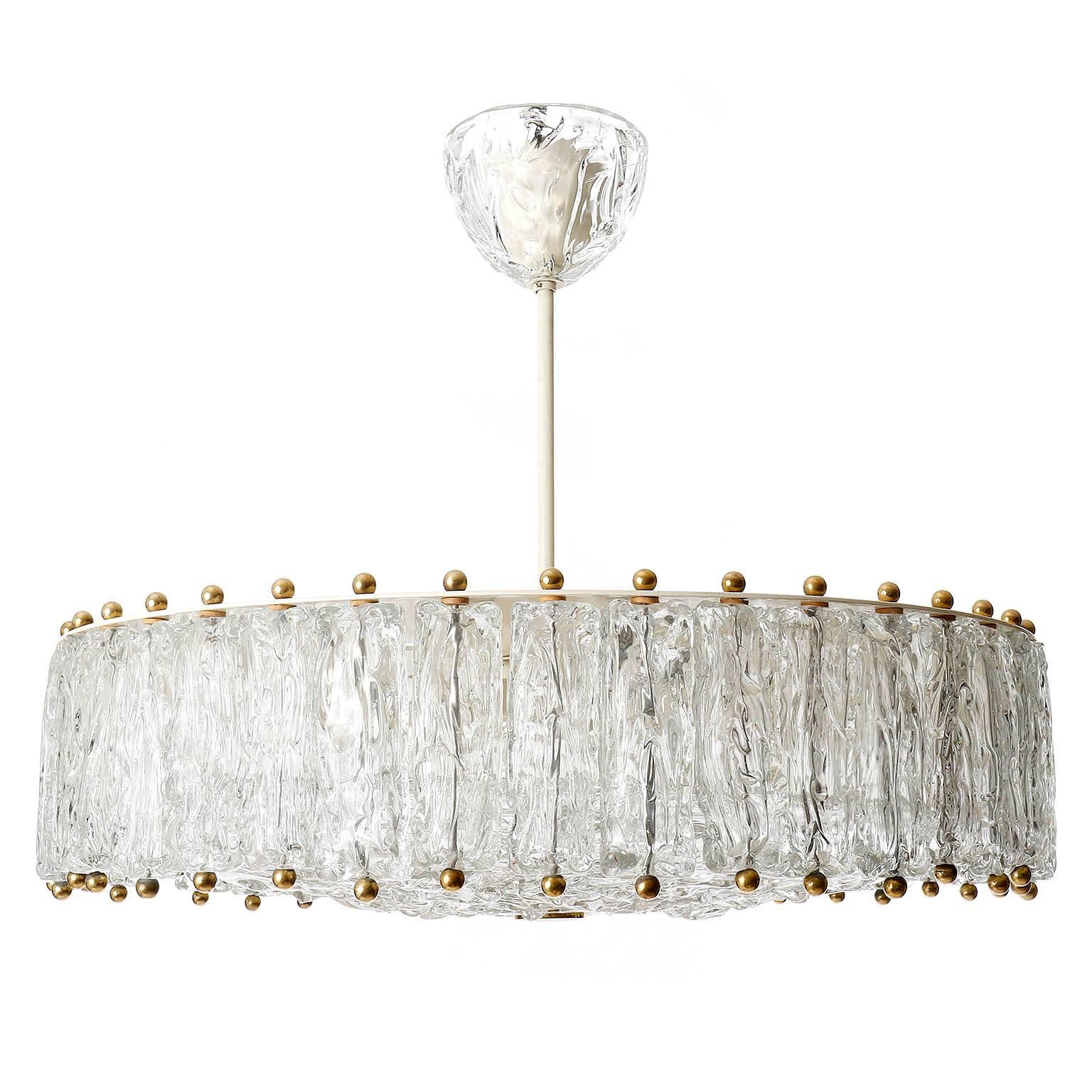 A large textured glass chandeliers or flush mounts by Vereinigte Werkstätten München, Germany, manufactured in Mid-Century, circa 1960.
Several glasses hung around a glass disk with brass hardware.
The glass is attributed to Aureliano Toso, circa