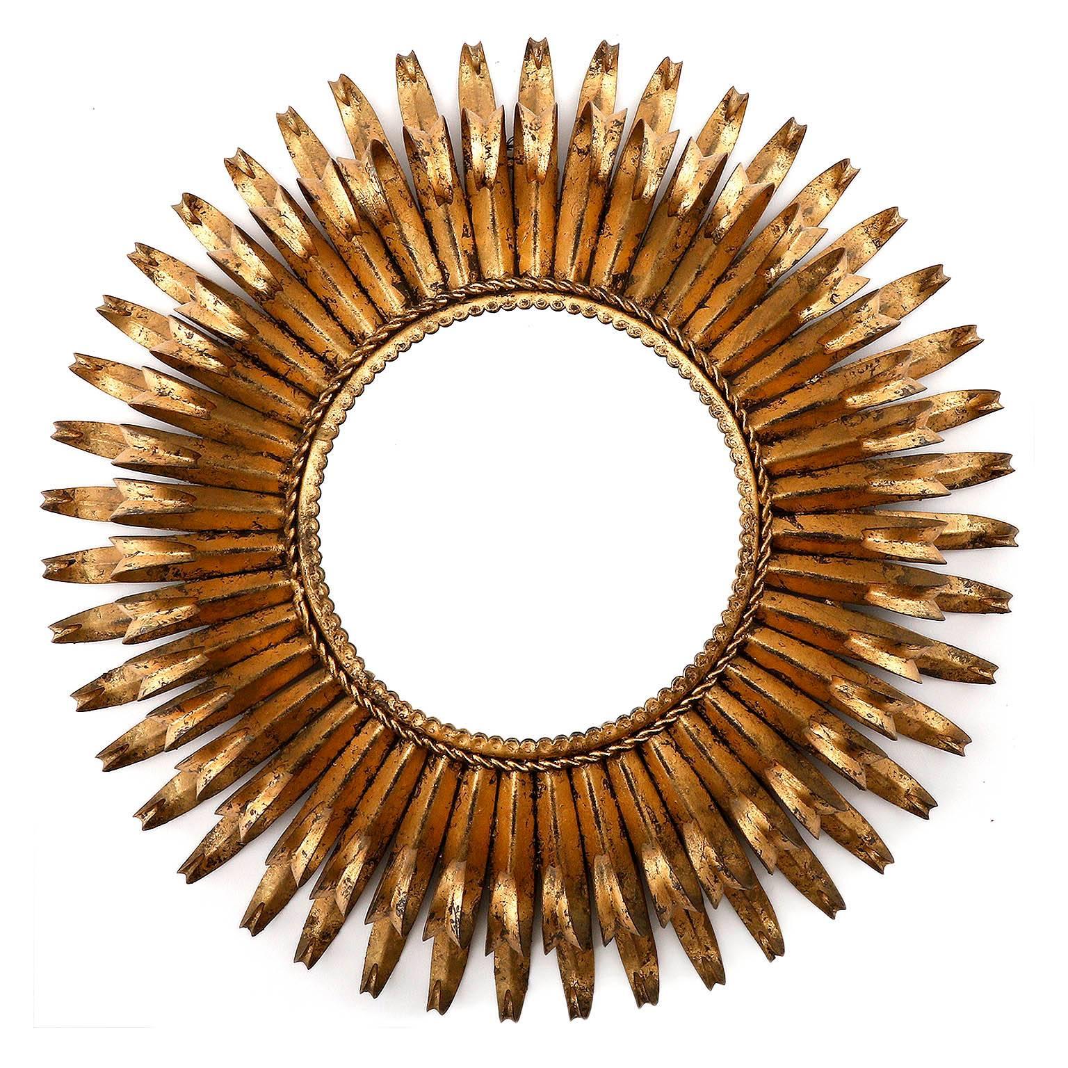 A beautiful gilt iron sunburst mirror with gold leaf finish and circular shape.
It has a lovely original vintage patina.
This very decorative piece was manufactured in France in Mid-Century in 1950s or 1960s.
  