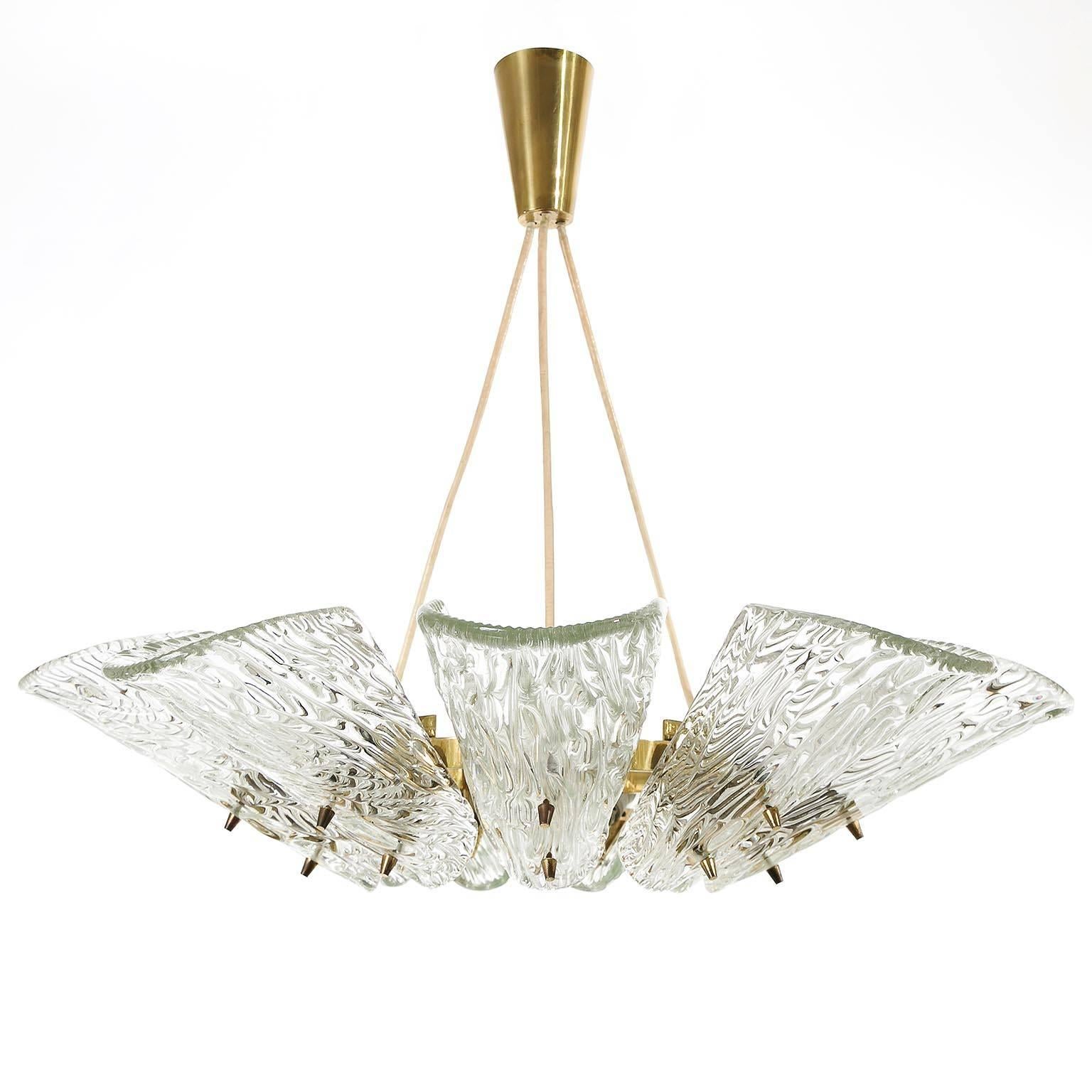 A Viennese textured glass and brass pendant light or chandelier by J. T. Kalmar, Austria, manufactured in midcentury, circa 1960 (late 1950s or early 1960s). 
This fixture is an impressive and handmade piece. It features nine arms with sockets for