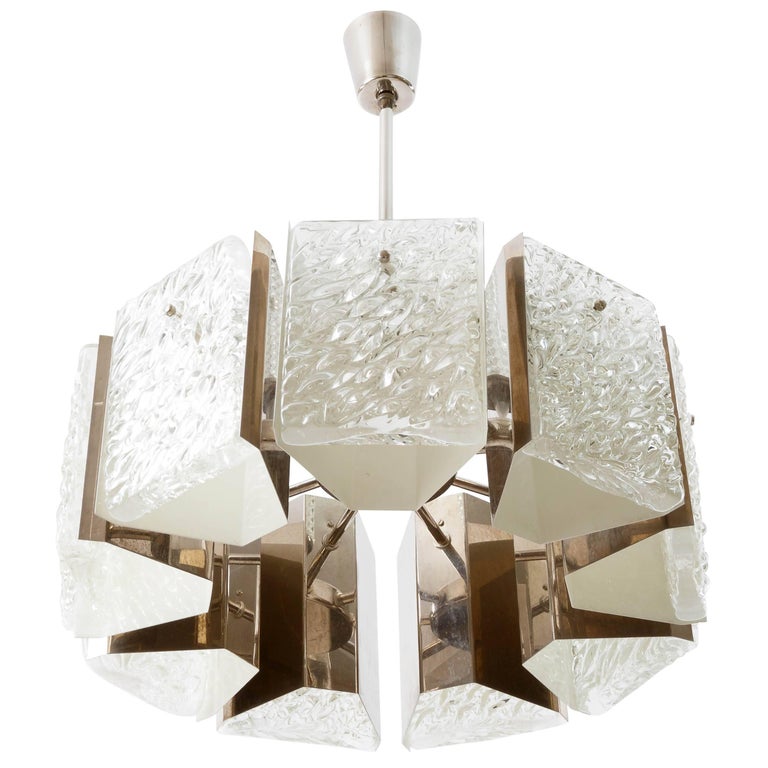A light fixture by Rupert Nikoll, Austria, manufactured in Mid-Century, circa 1960 (late 1950s or early 1960s). 
It is made of a nickeled (similar to chrome) frame which holds nine large textured glass pieces. The glass is in the style of the lights