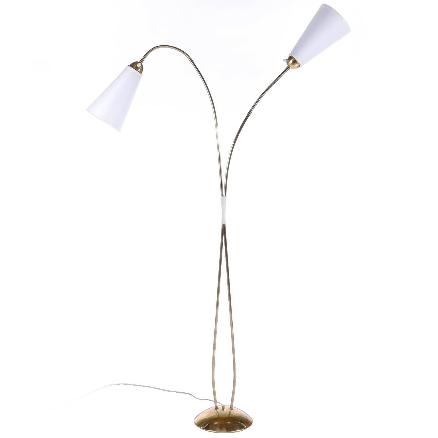 A brass floor lamp with two flexbile arms by Rupert Nikoll, Vienna, Austria, manufactured in Mid-Century, circa 1960 (late 1950s or ealry 1960s).
The stand is made of two curved brass rods with a handle made of a white plastic string. At the end of