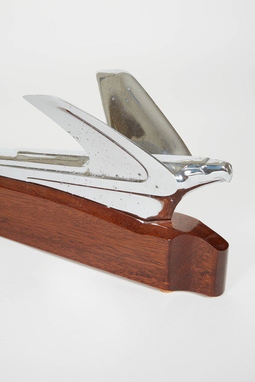 American hood ornament from a 1950s Ford Skyliner. The hood ornament is mounted on wood. This item makes both a unique gift for a vintage car enthusiast or a conversational piece for an office.