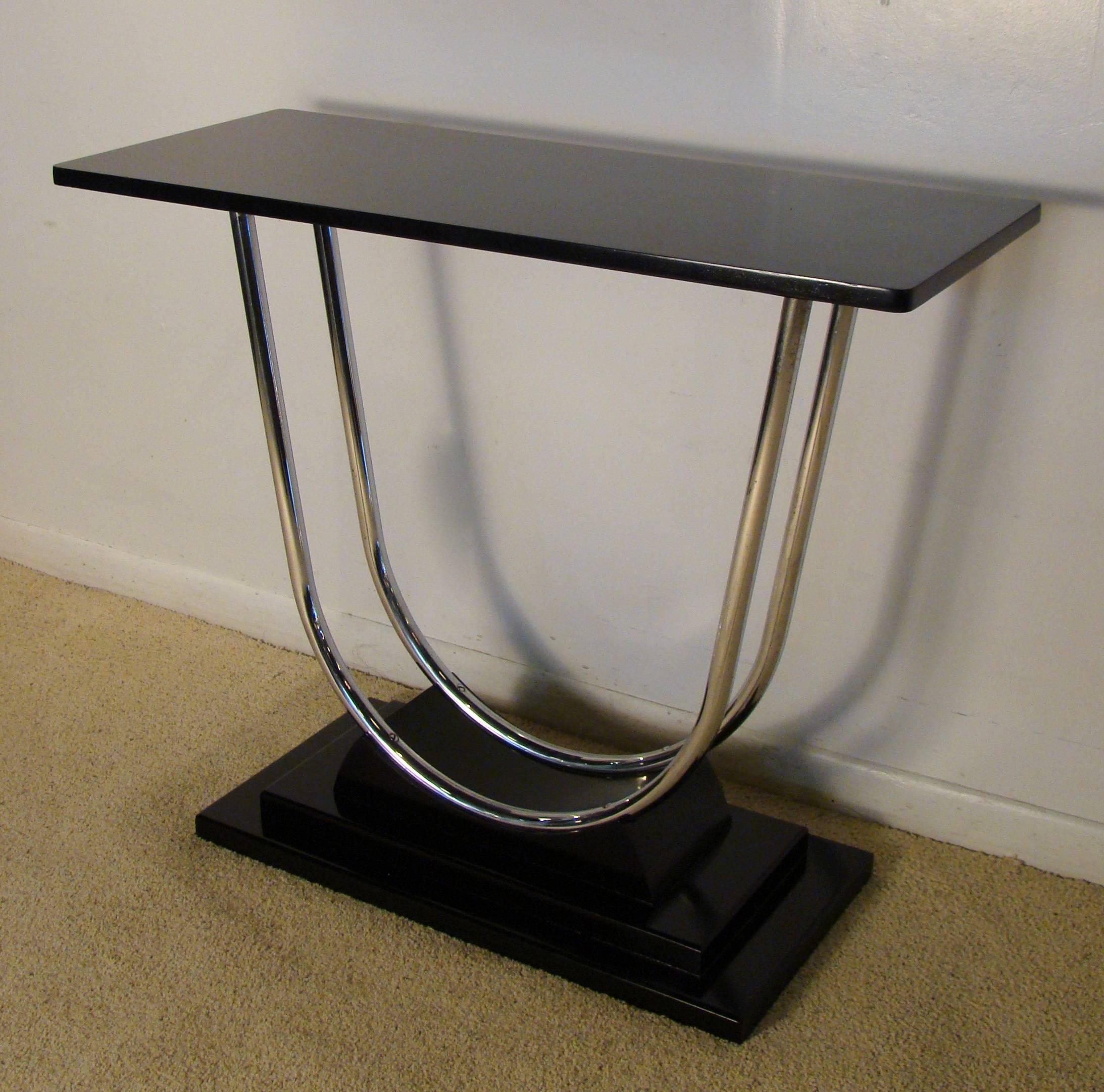Exceptional Machine Age Art Deco tubular chrome console table that sits on a stepped base, circa 1930s. This piece is beautiful from every angle and quite versatile. Black lacquer and chrome.