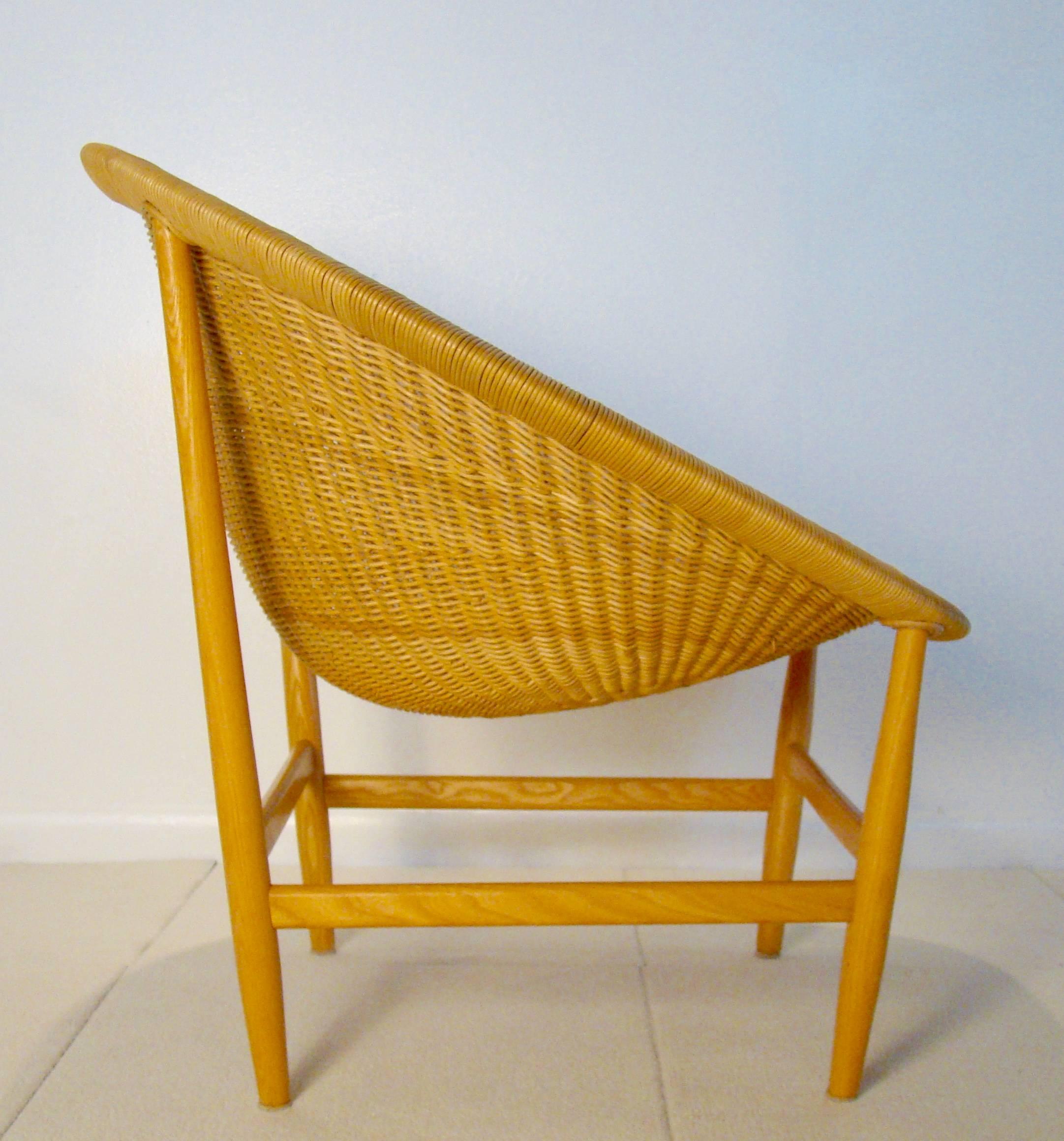 Beautiful wicker basket lounge chair sometimes referred to as the Pontoppidan chair. A wood frame comprised of birch wood slips into the wicker chair piece supported by stretchers. Comfortable and scuptural. Simple and understated.