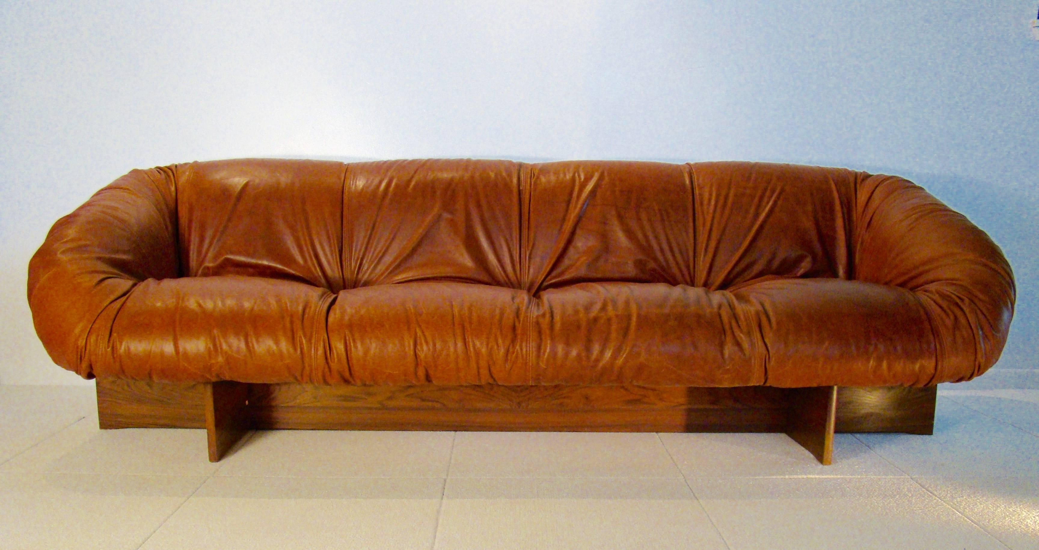 Very uncommon offering, this three-seat sofa contrasts a matte
white fibreglass shell against Percival Lafer's signature rustic leather upholstery cradled in a rosewood plynth base.

Beautiful, amorphic, newer cognac leather upholstery with