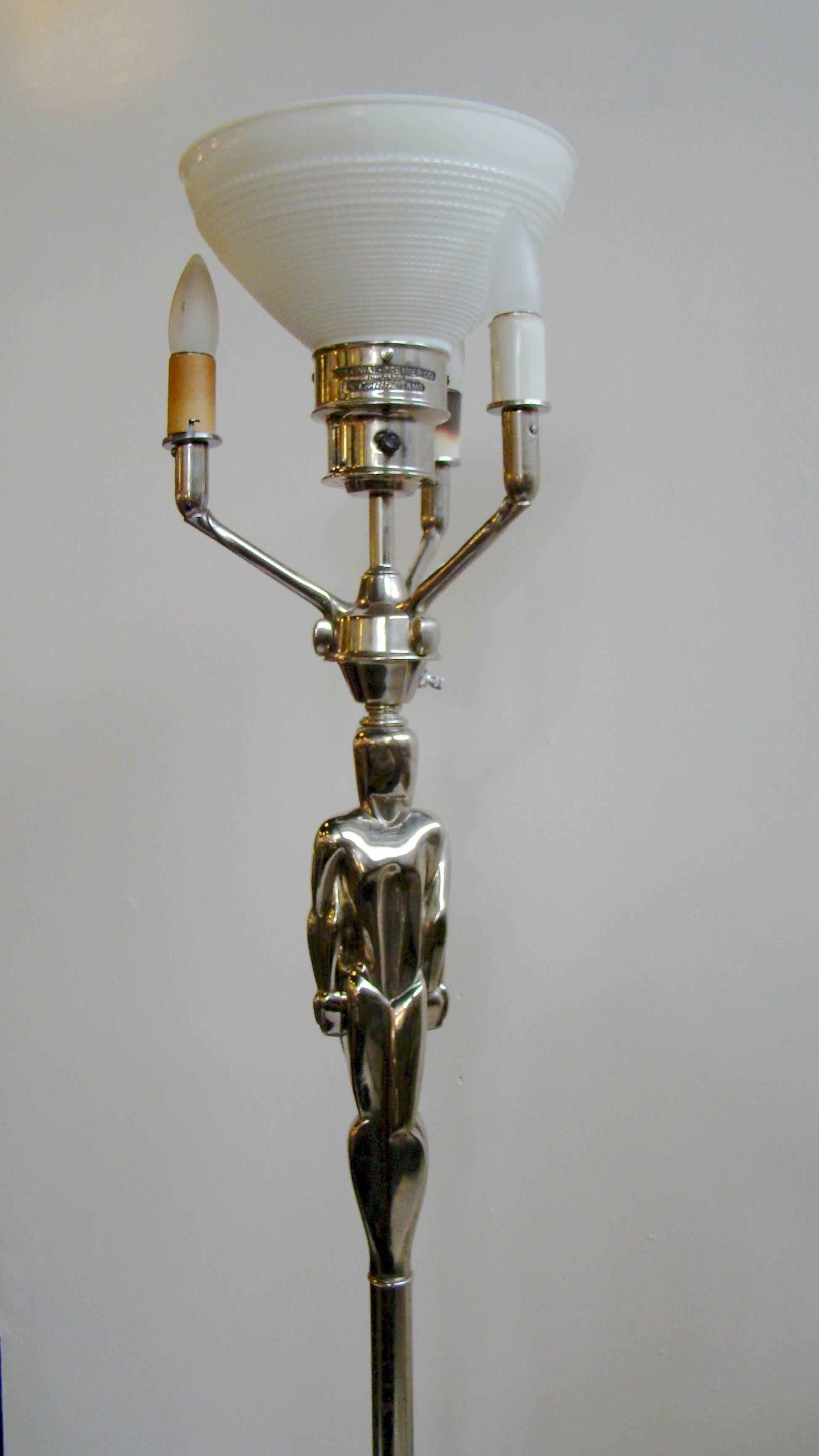 Exquisite Art Deco floor chrome steel floor lamp depicting a cubist male and female intertwined. It features a three way switch for the small lights to the outside of the shade and a separate switch for the bulb inside the shade. The shade is a