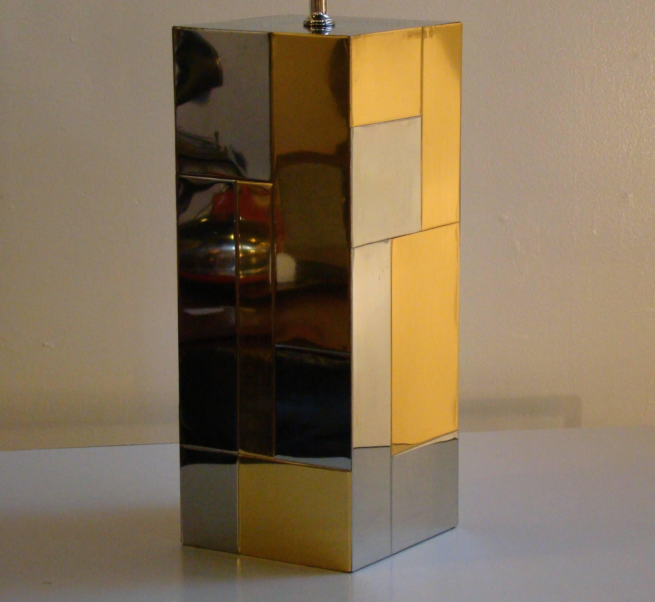 This table lamp features alternating chrome and brass patchwork on the base and the original shade and finial. This is the Cityscape series which Paul Evans designed for Directional furniture. Base measures 7.25 x 7.25 x 18. Illuminates the room