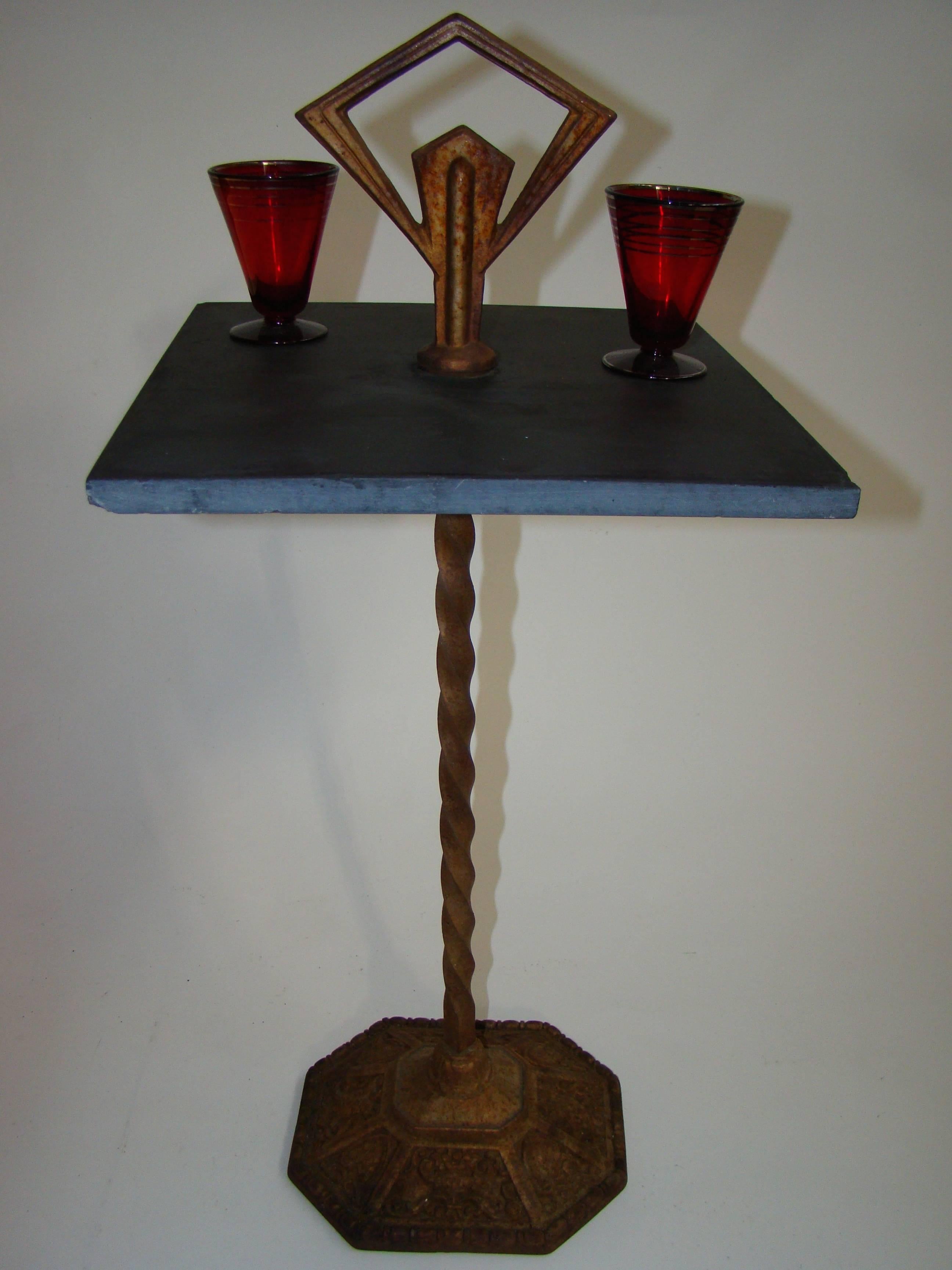 Beautiful cast iron and slate cocktail table/smoke stand ca. 1930s.  The top is a cast iron deco motif with a barley twist support connected to deco motif base.  The center is slate.